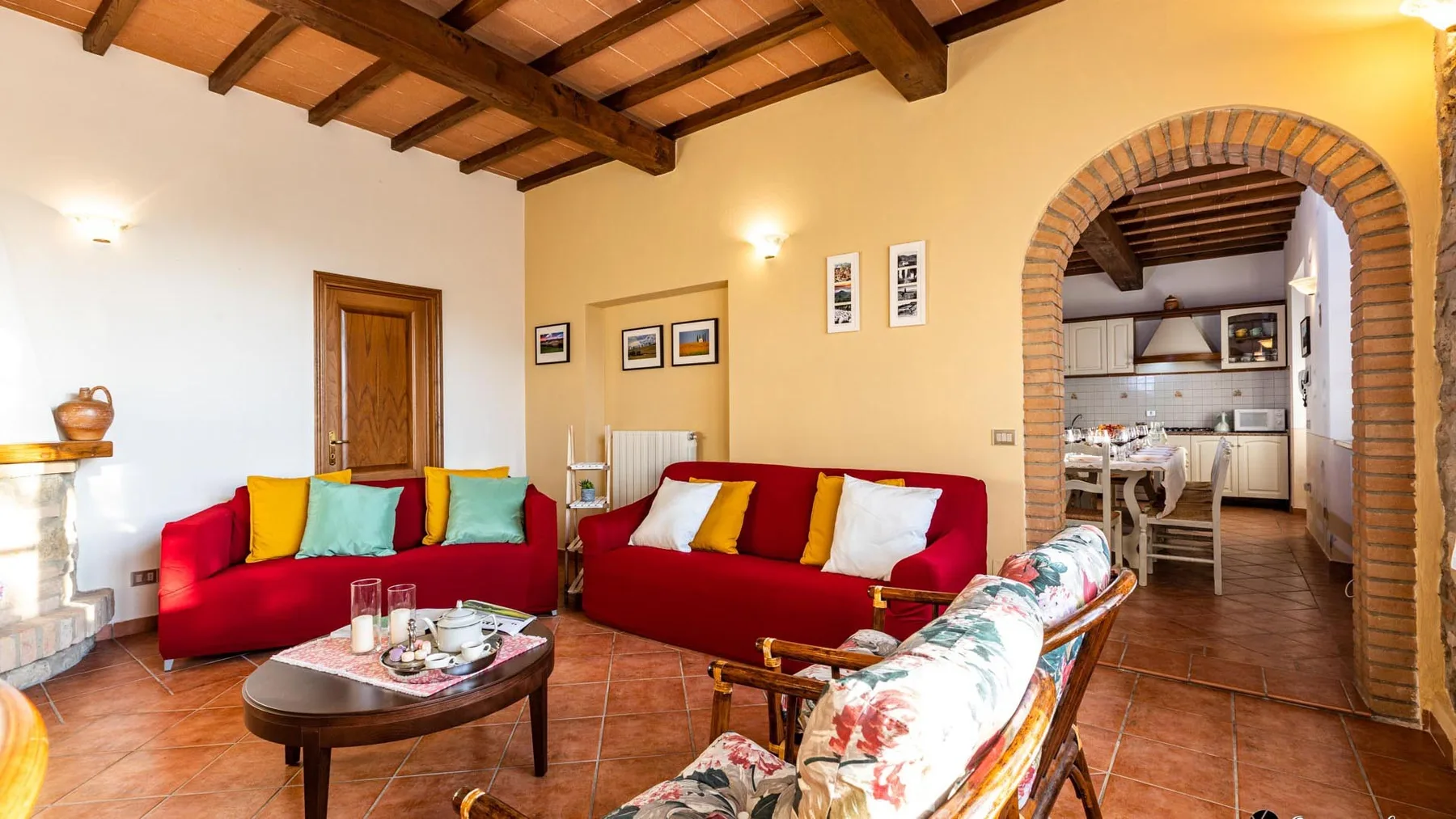 Una sala de estar con asientos rojos, una mesa de centro y un arco que da a la cocina.