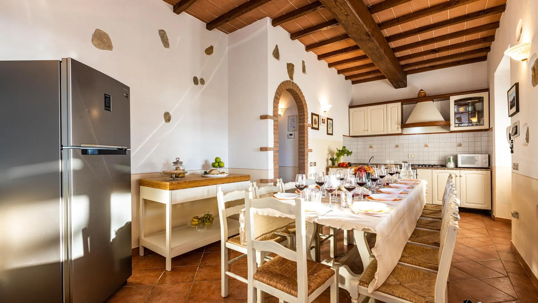 Comedor con una mesa larga preparada para comer y una cocina al fondo.
