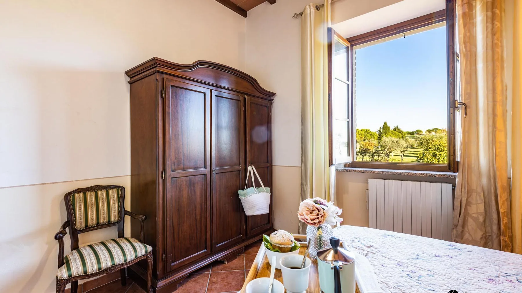 Un dormitorio con un armario de madera oscura, una cama y una ventana abierta.
