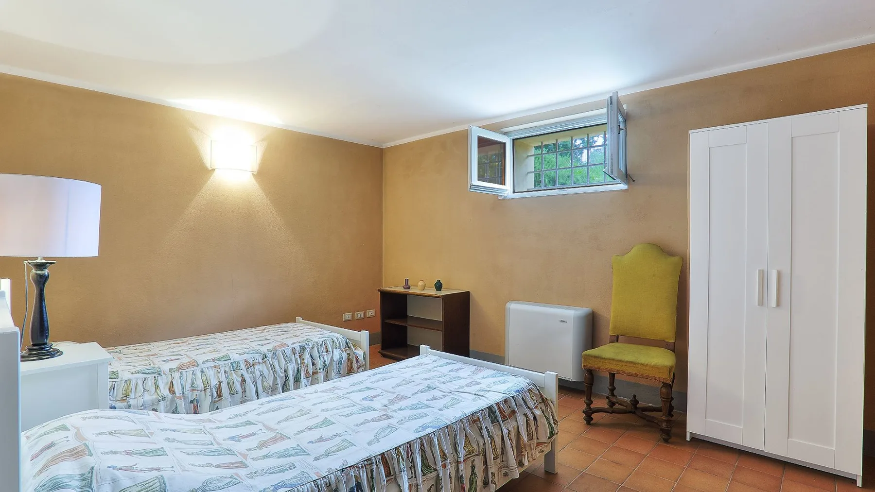 Un dormitorio con dos camas, una silla amarilla y un armario blanco.