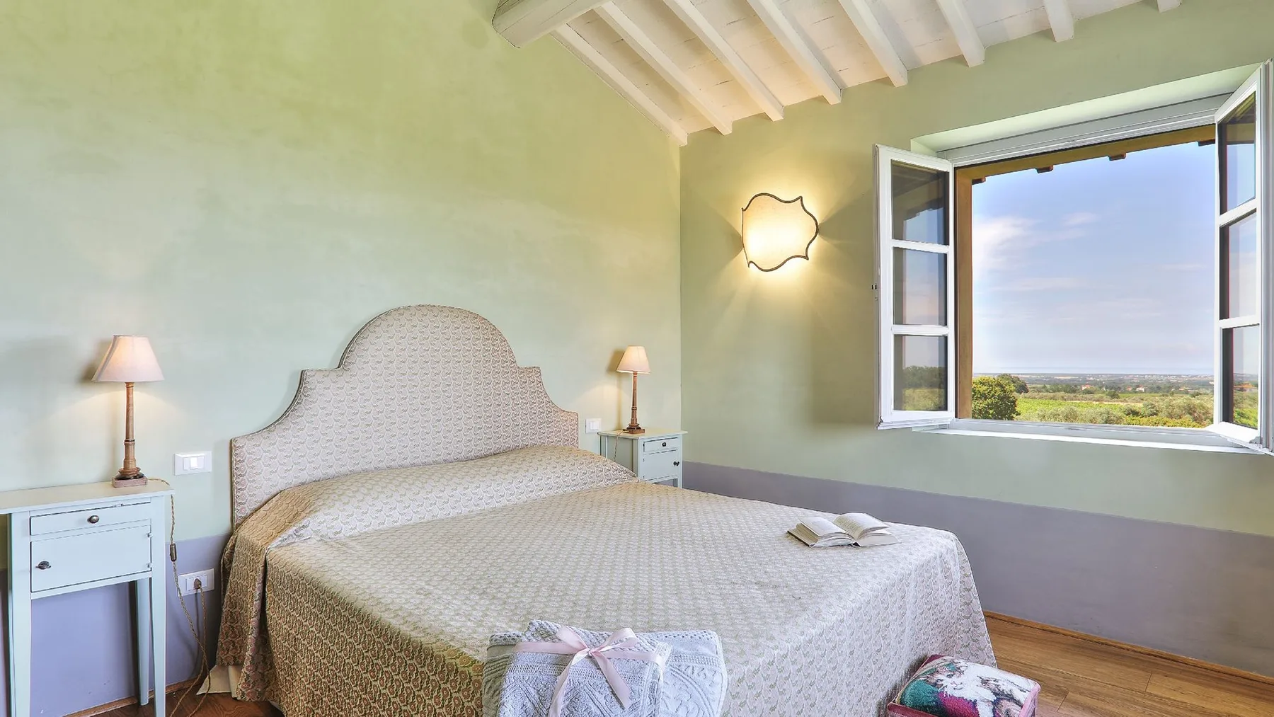 Un dormitorio con una cama grande y una ventana abierta con vistas al paisaje.
