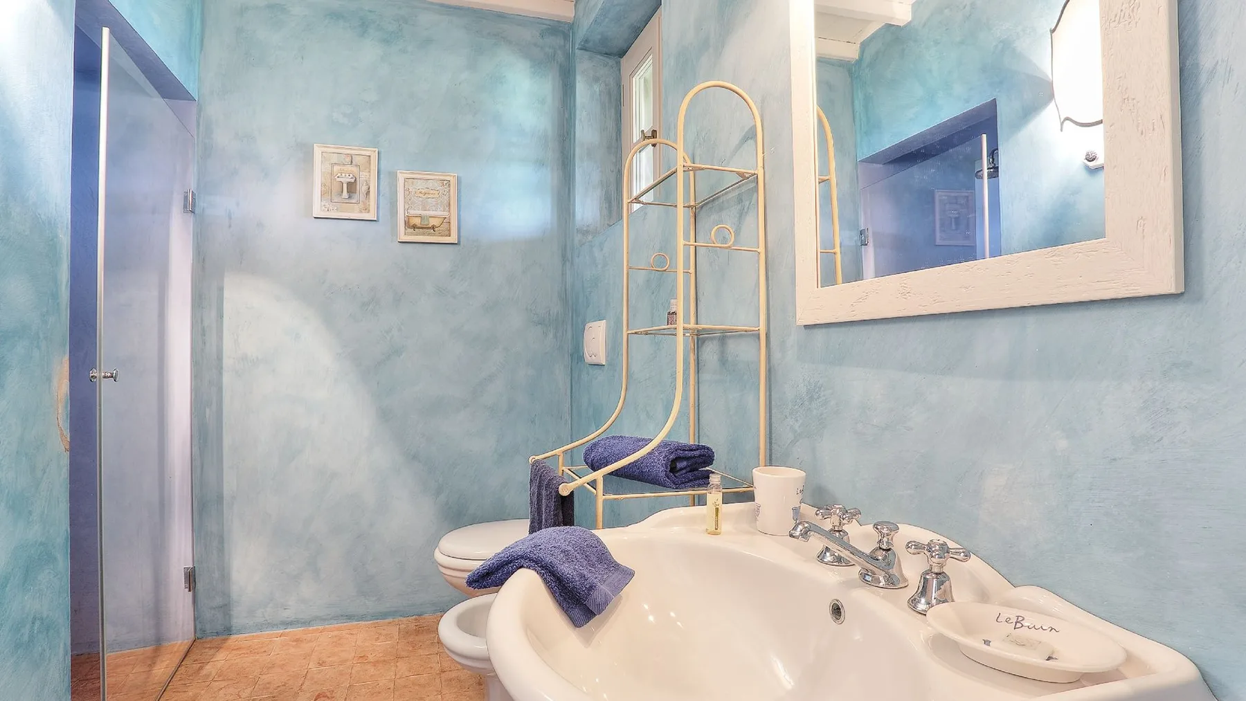 Un baño con una bañera grande, dos lavabos y un toallero dorado.