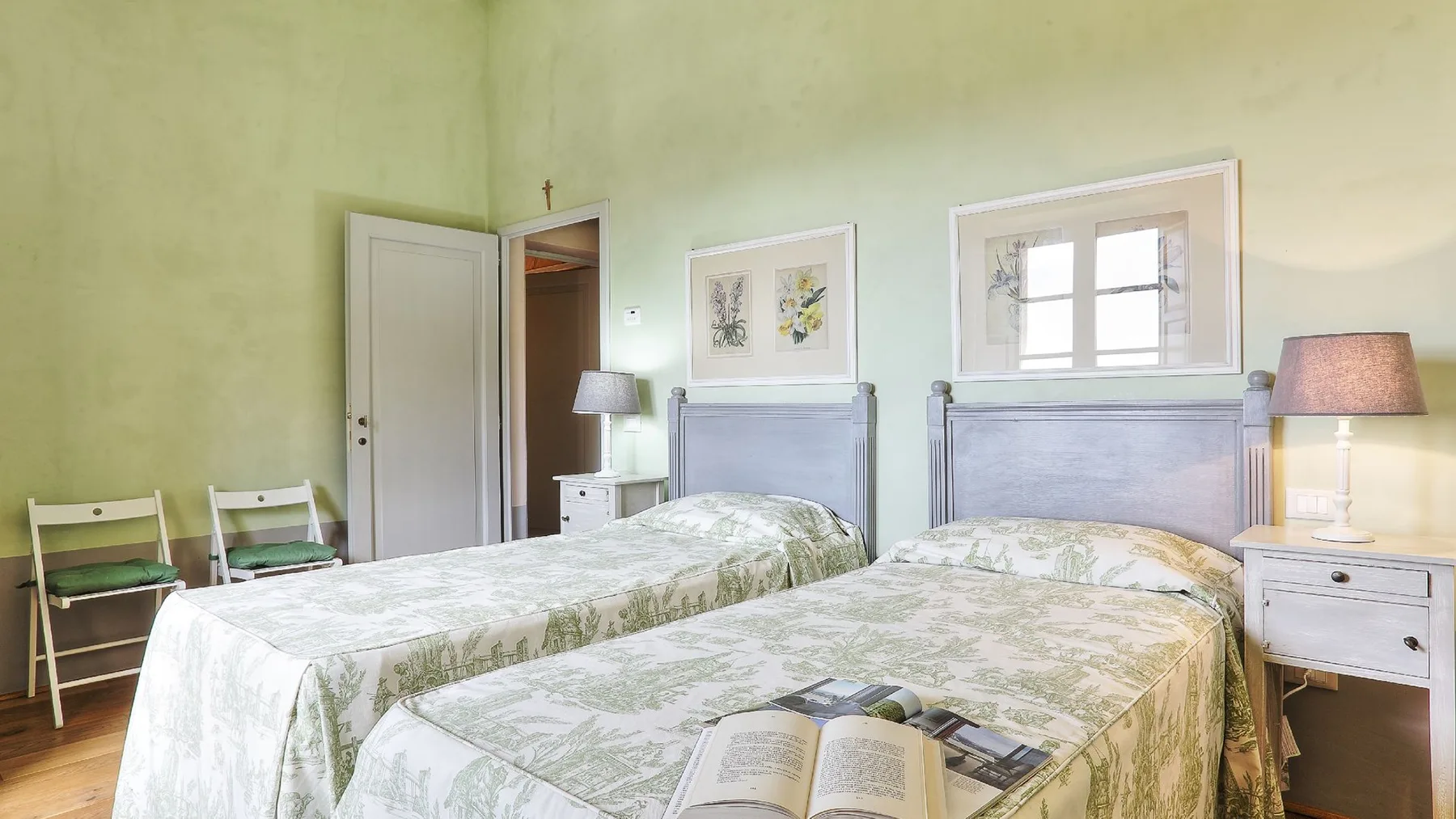 Un dormitorio con dos camas cubiertas con ropa de cama estampada clara.