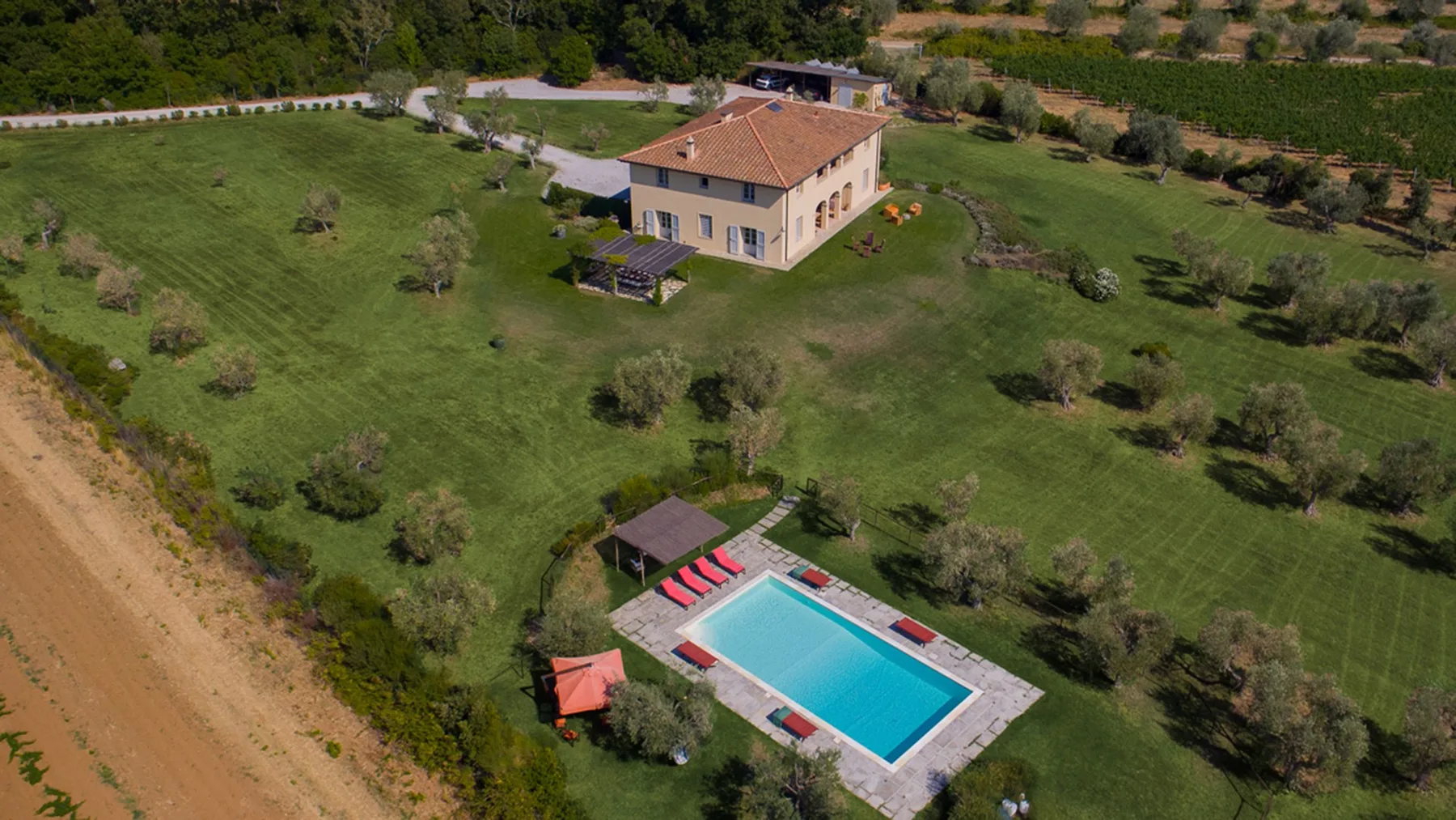 Vista aérea de una casa y una piscina en un paisaje de césped.