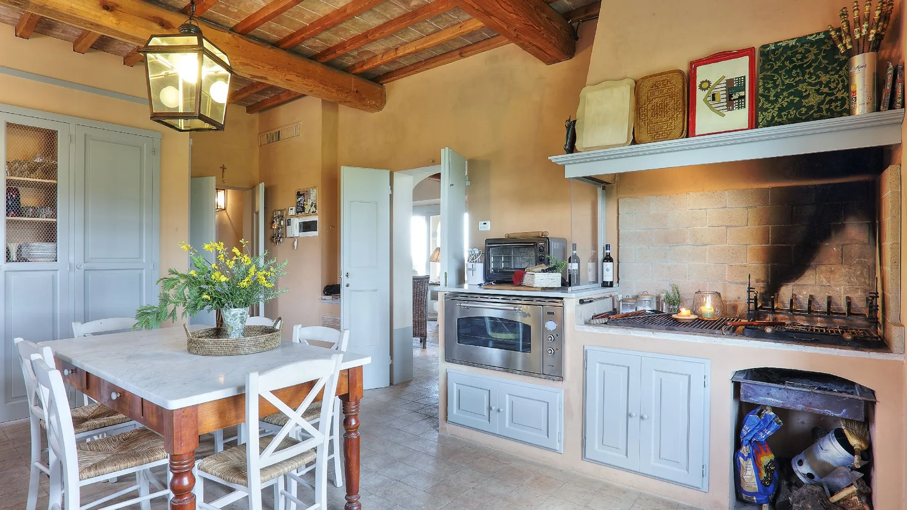 Una cocina rústica con una mesa de comedor, armarios claros y una gran chimenea.
