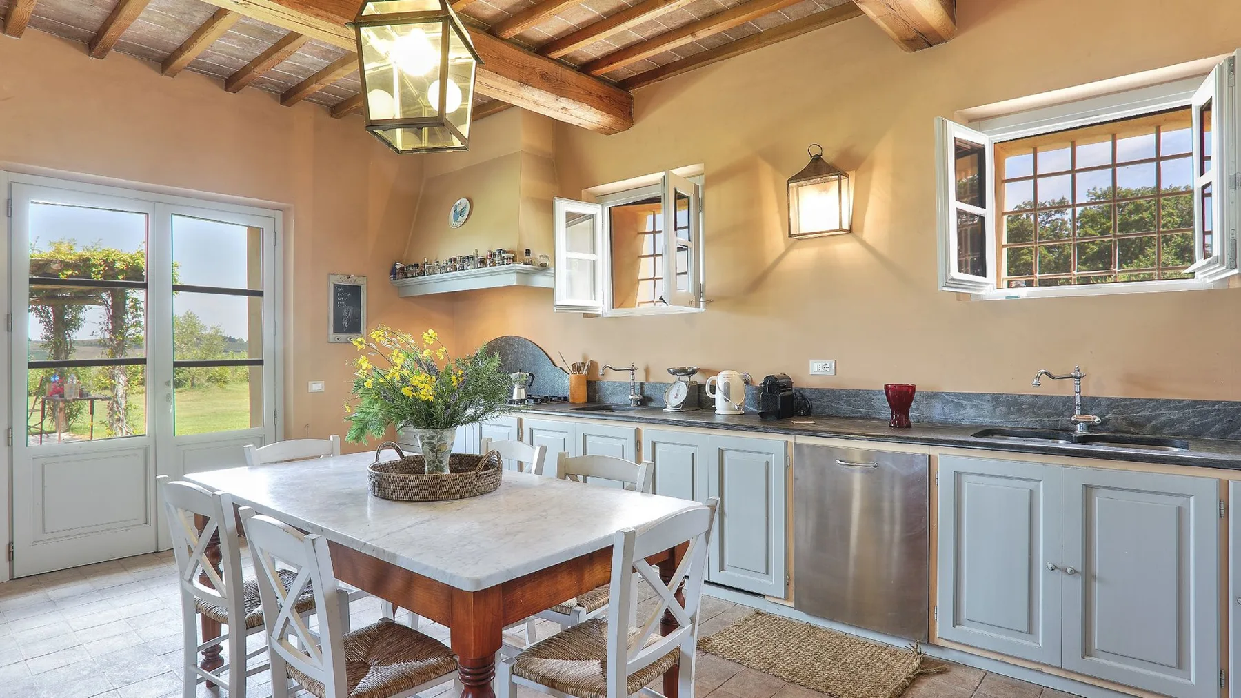 Una cocina luminosa con una mesa grande en el centro y ventanas con vistas a la vegetación.