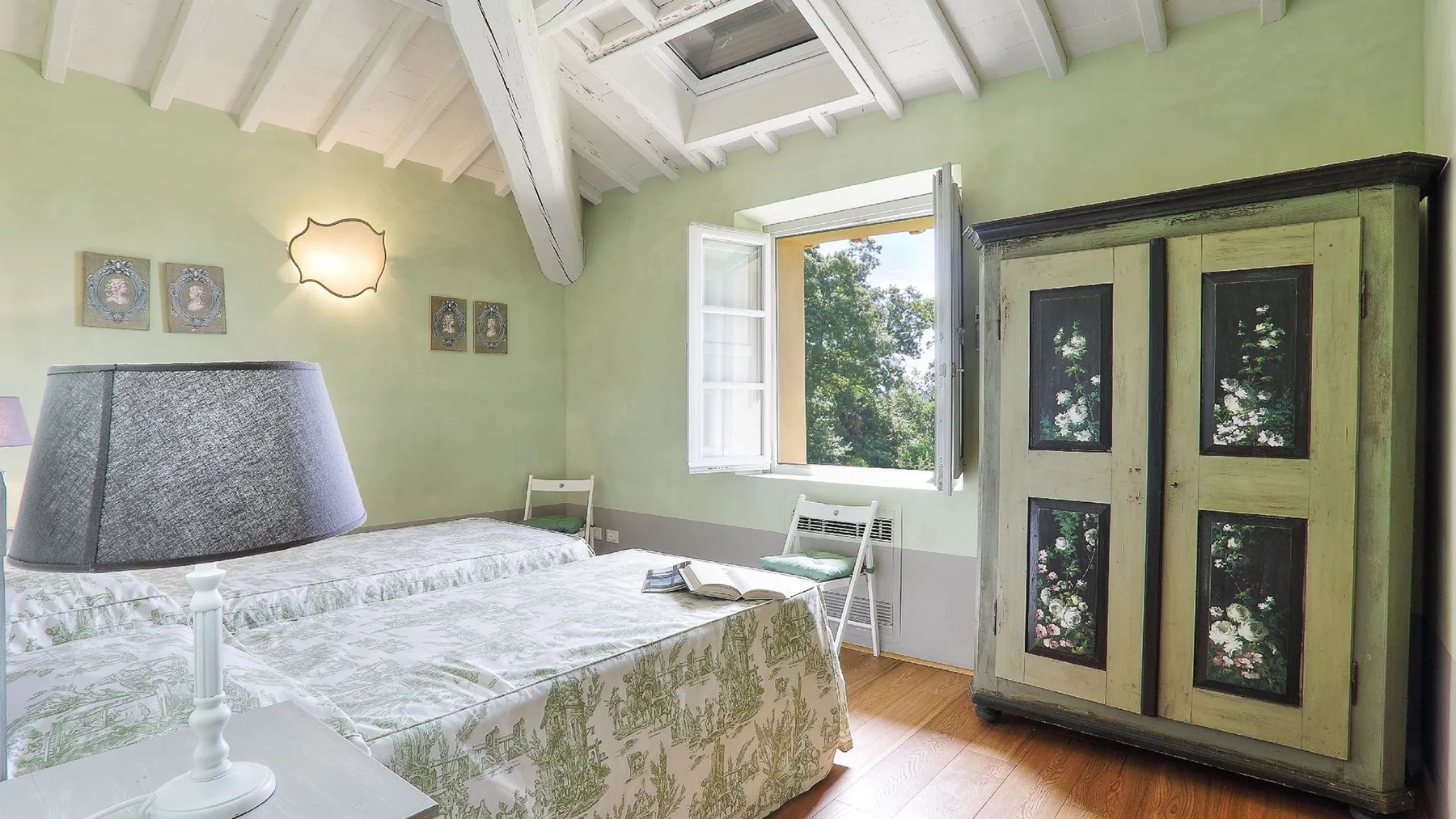 Un dormitorio con una cama junto a una ventana abierta y un armario grande.