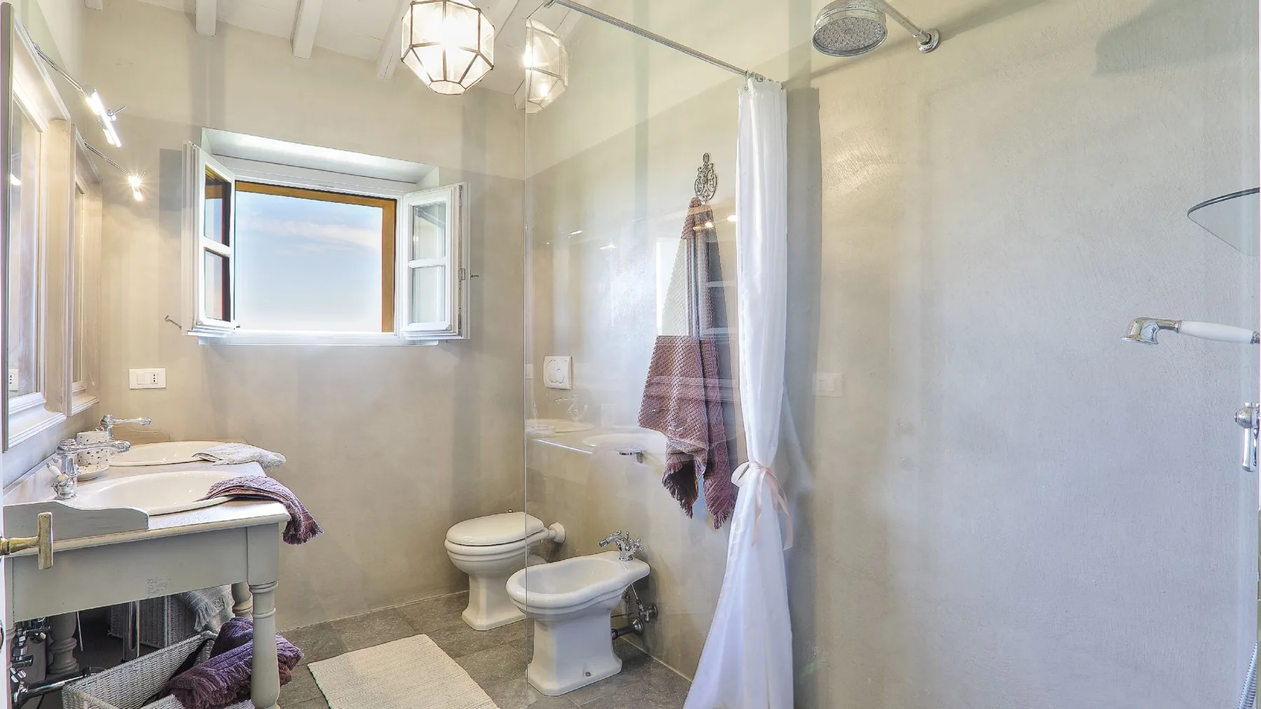 Un baño luminoso con lavabo, inodoro y ducha.