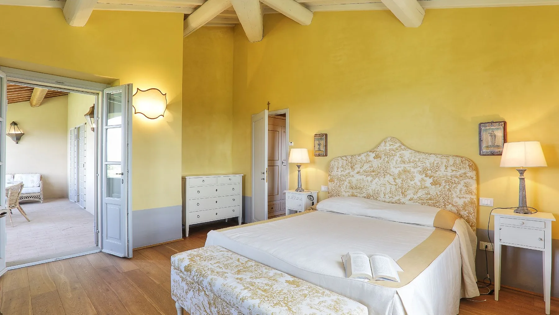Un dormitorio con una cama, mesitas de noche y paredes amarillas.