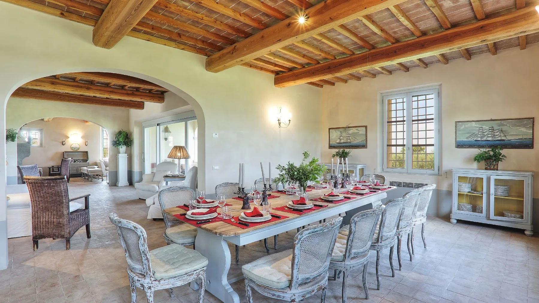 Un comedor con una mesa larga preparada para una comida bajo vigas de madera.