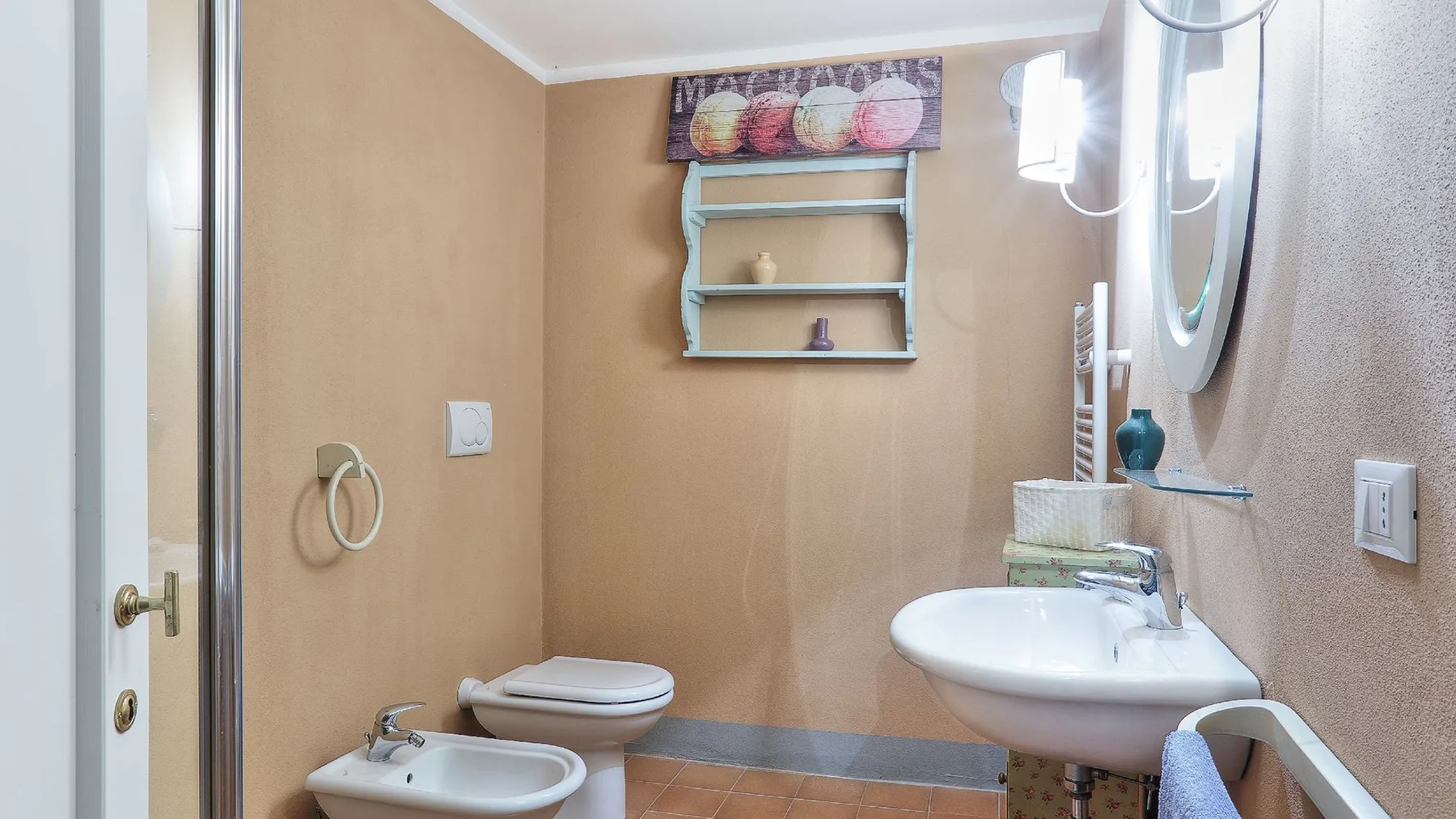 Un baño con lavabo, inodoro y pequeños estantes de pared.