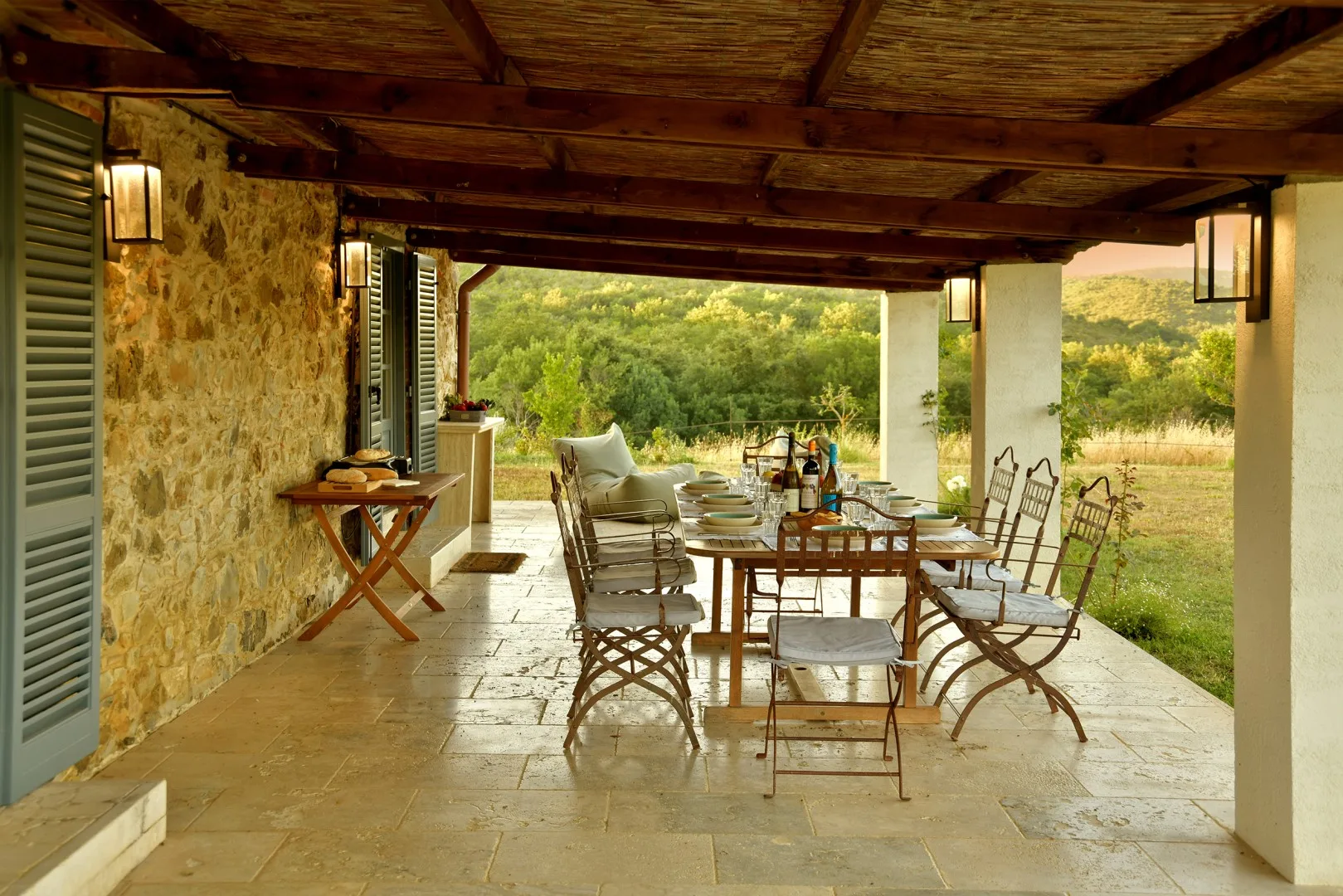 Un comedor exterior cubierto, con una mesa larga y sillas, da a un paisaje verde.