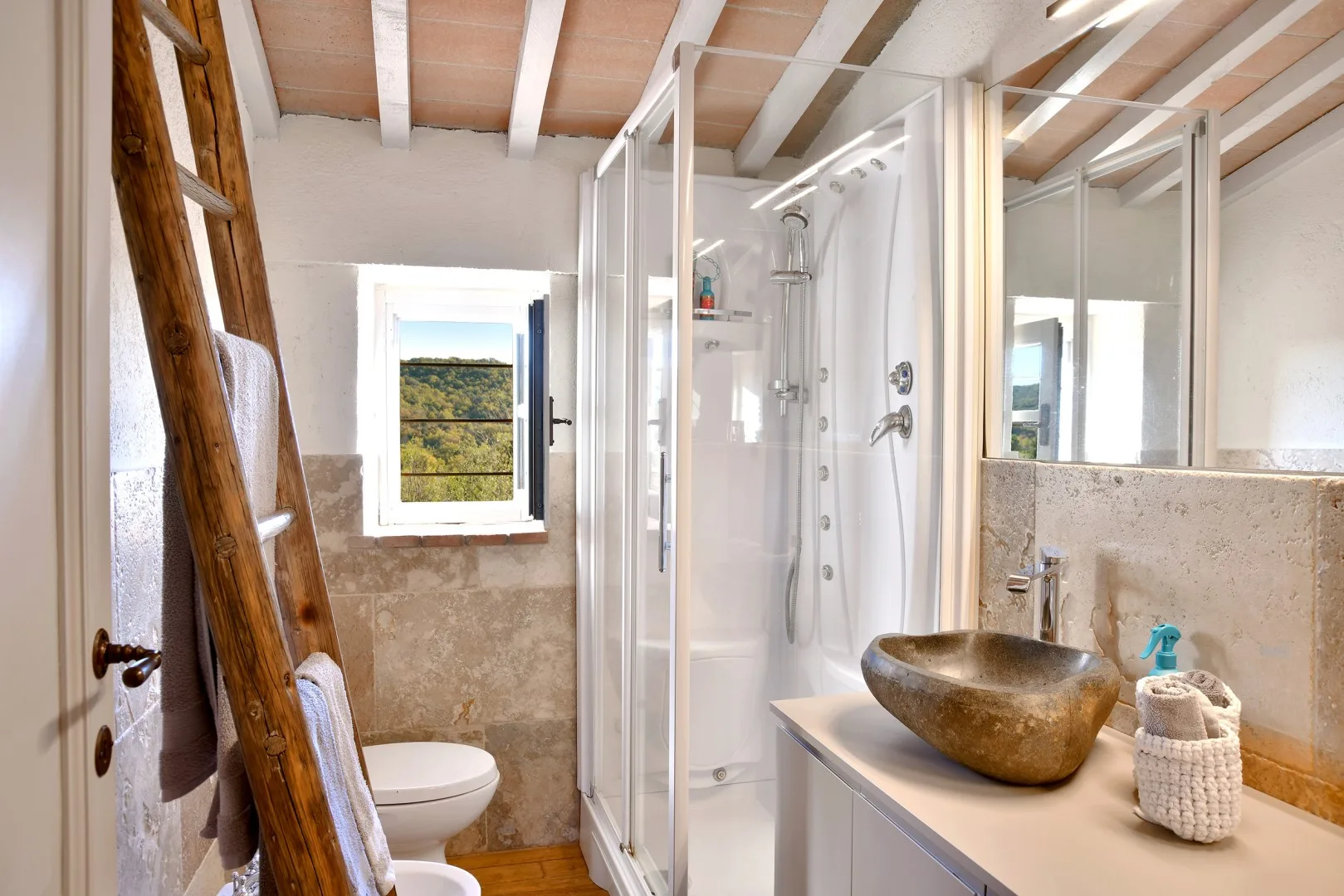 Un baño luminoso con ducha de vidrio y lavabo de piedra.