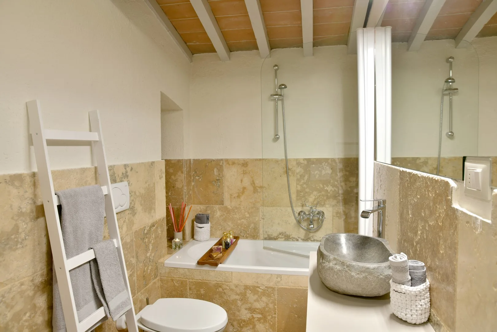 Un baño con bañera, ducha y lavabo bajo un techo de madera.