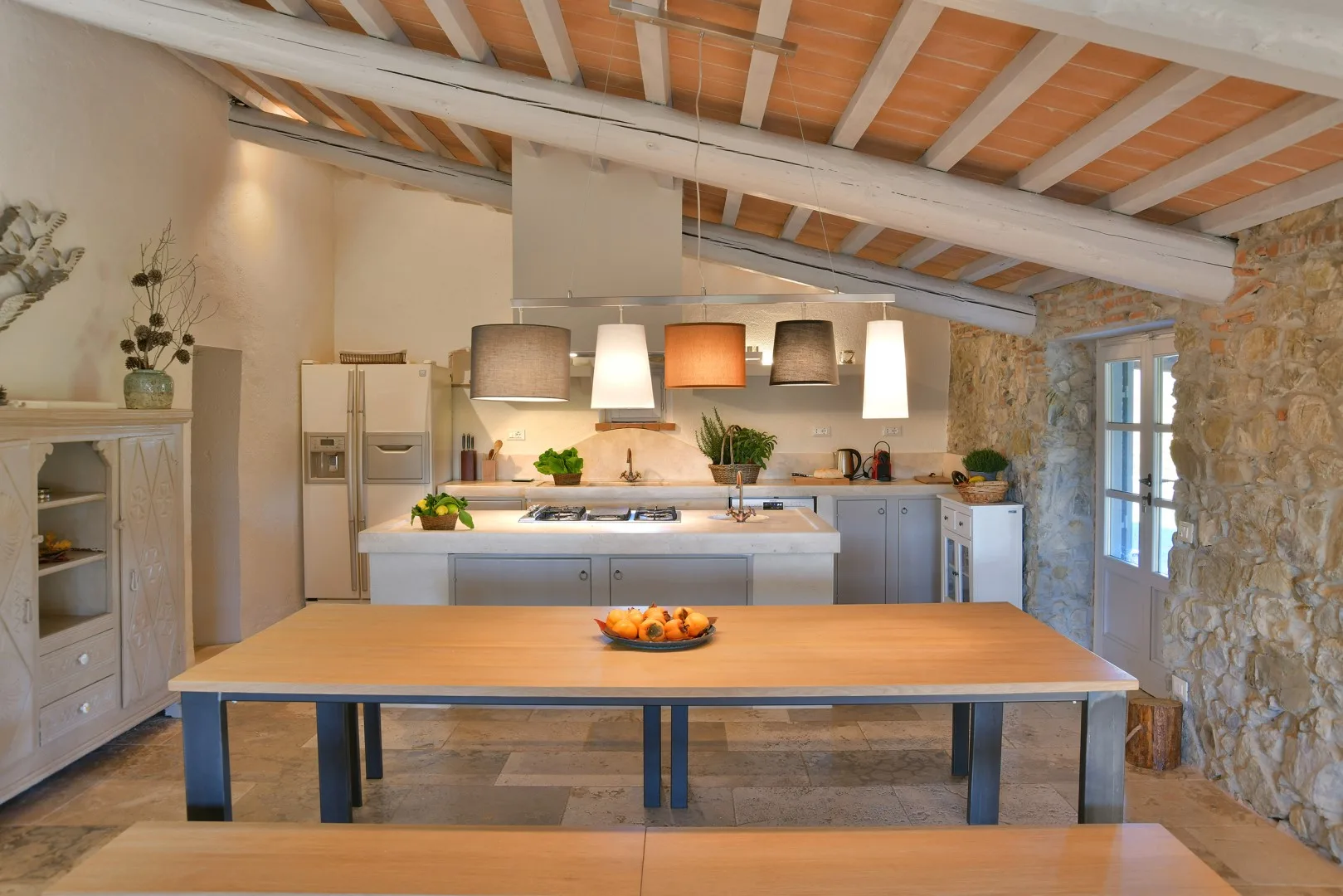 Una cocina amplia con una gran mesa de madera y lámparas colgantes.