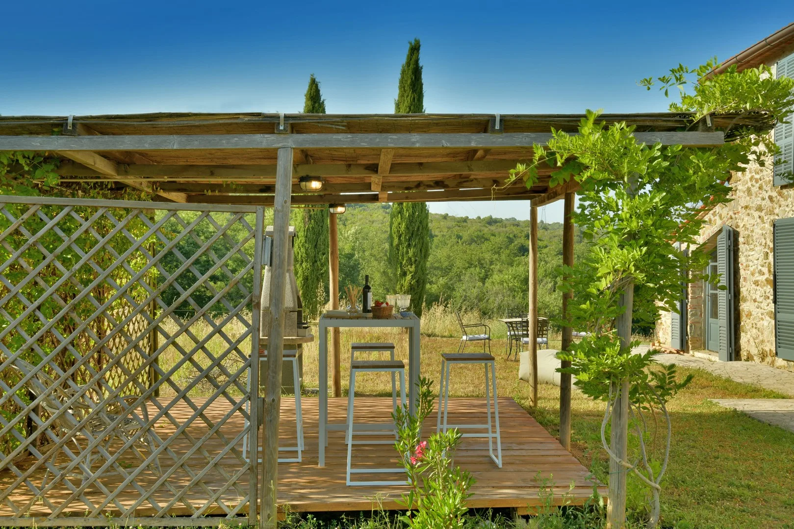 Un patio exterior cubierto con tarima de madera y asientos de barra da a colinas verdes.