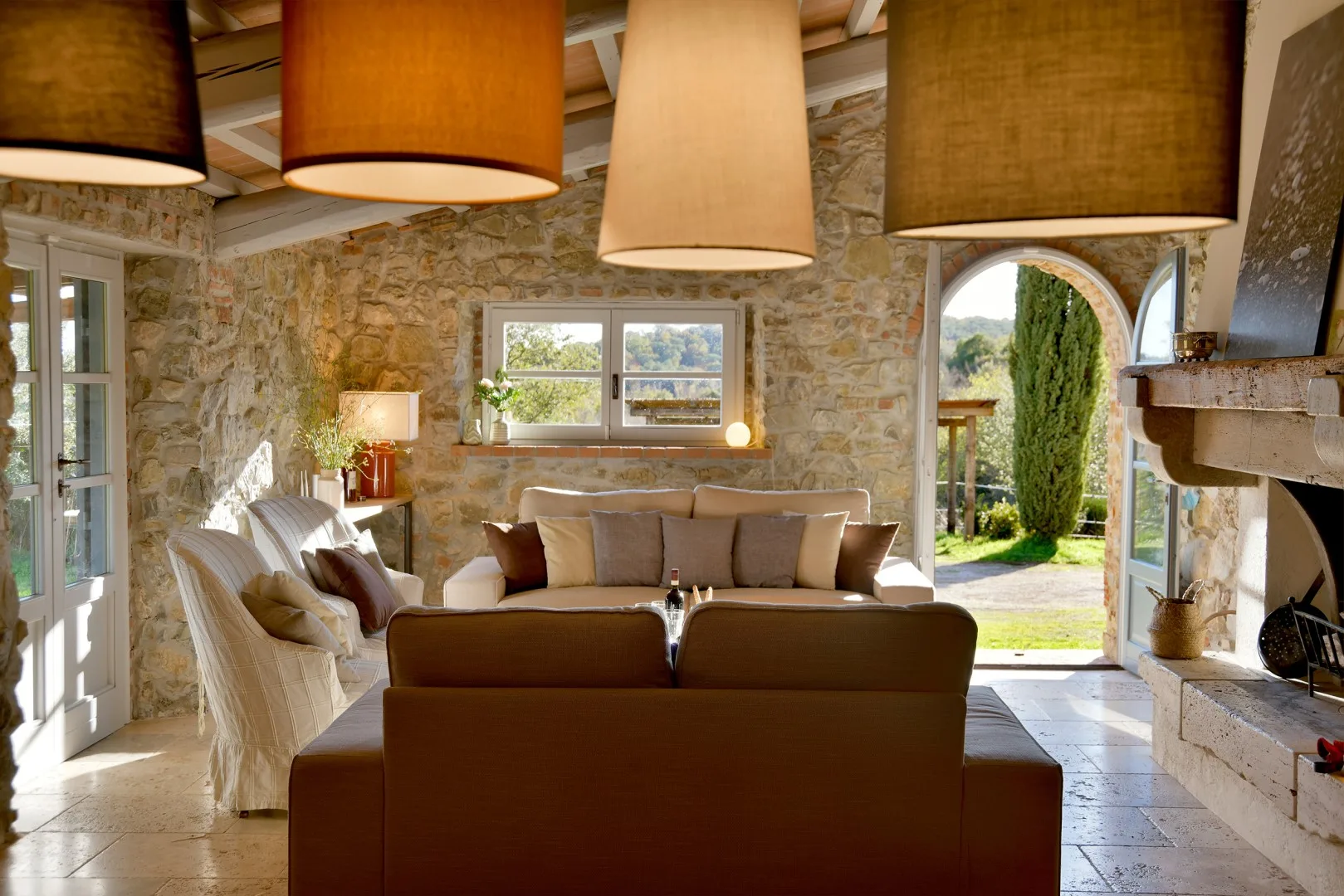 Una sala de estar de piedra con asientos junto a una chimenea y una vista al exterior.