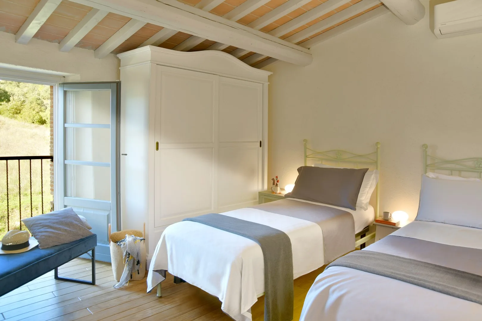 Un dormitorio con dos camas, un armario y una puerta abierta al balcón.