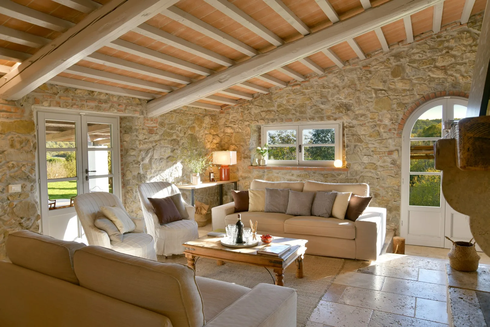 Una sala de estar con paredes de piedra y asientos alrededor de una mesa baja de madera.