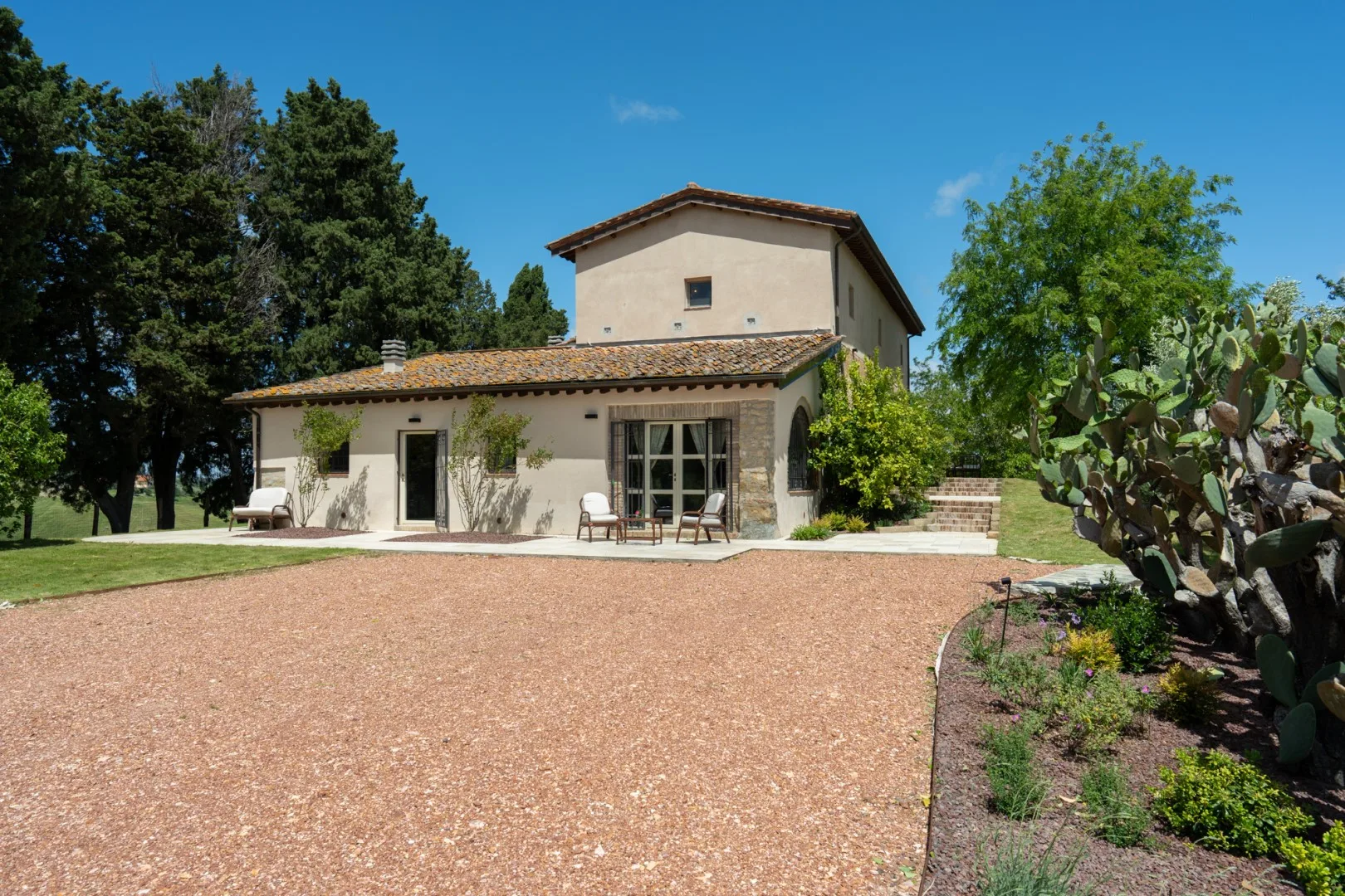 Una casa de dos plantas con patio, entrada de grava y jardín cuidado.
