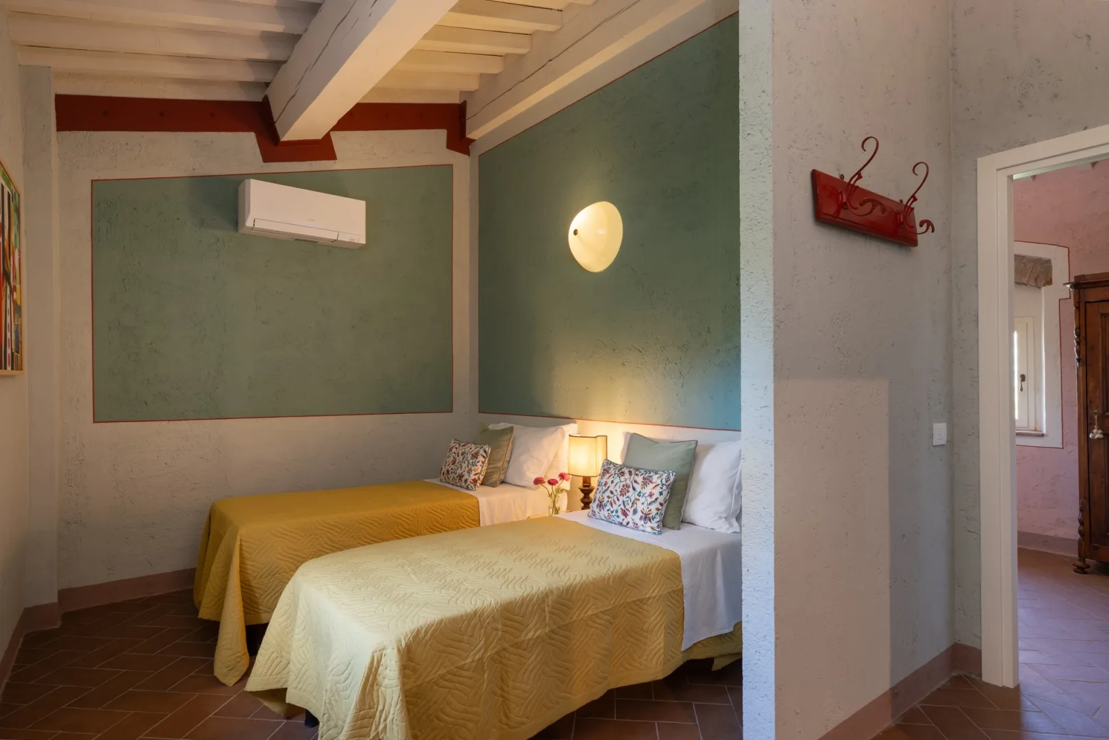 Un dormitorio con dos camas, un aire acondicionado de pared y una lámpara de noche.