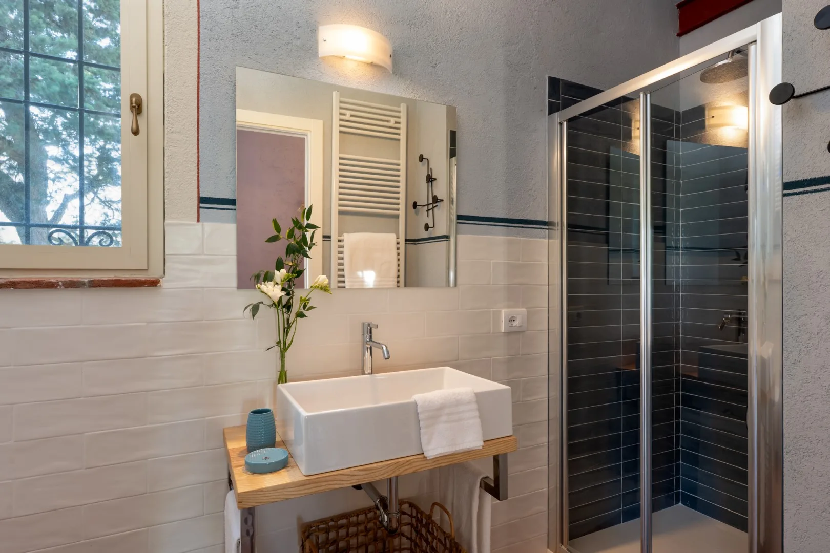 Un baño luminoso con lavabo, espejo y ducha de vidrio.
