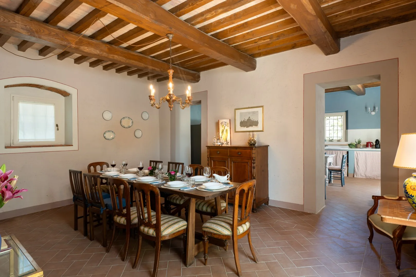 Un comedor con una mesa larga preparada bajo vigas de madera expuestas.