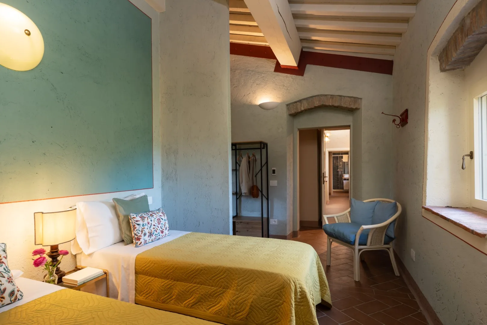 Un dormitorio con dos camas, una pared azul y una puerta que da a otra habitación.
