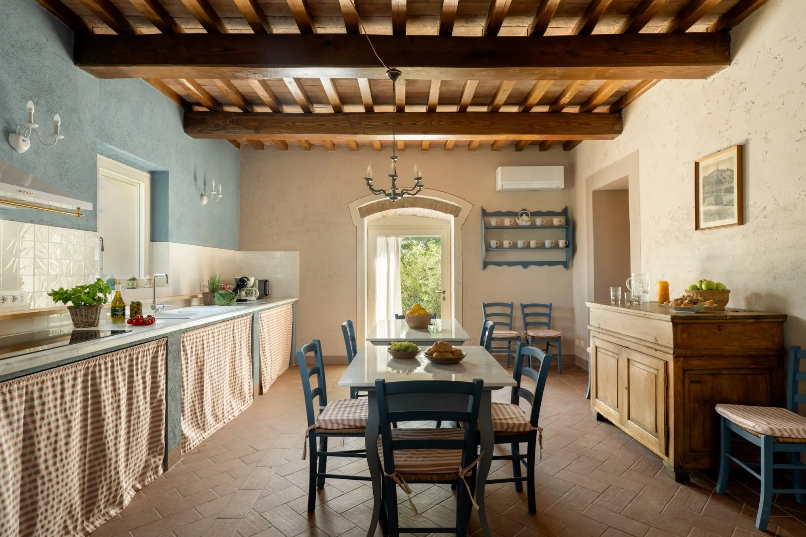 Una cocina rústica con comedor y una mesa larga bajo vigas de madera vistas.