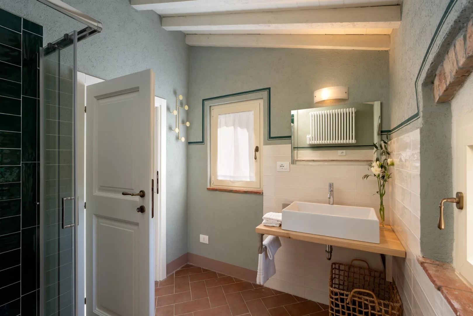 Un baño con lavabo sobre encimera, radiador de pared y zona de ducha alicatada.