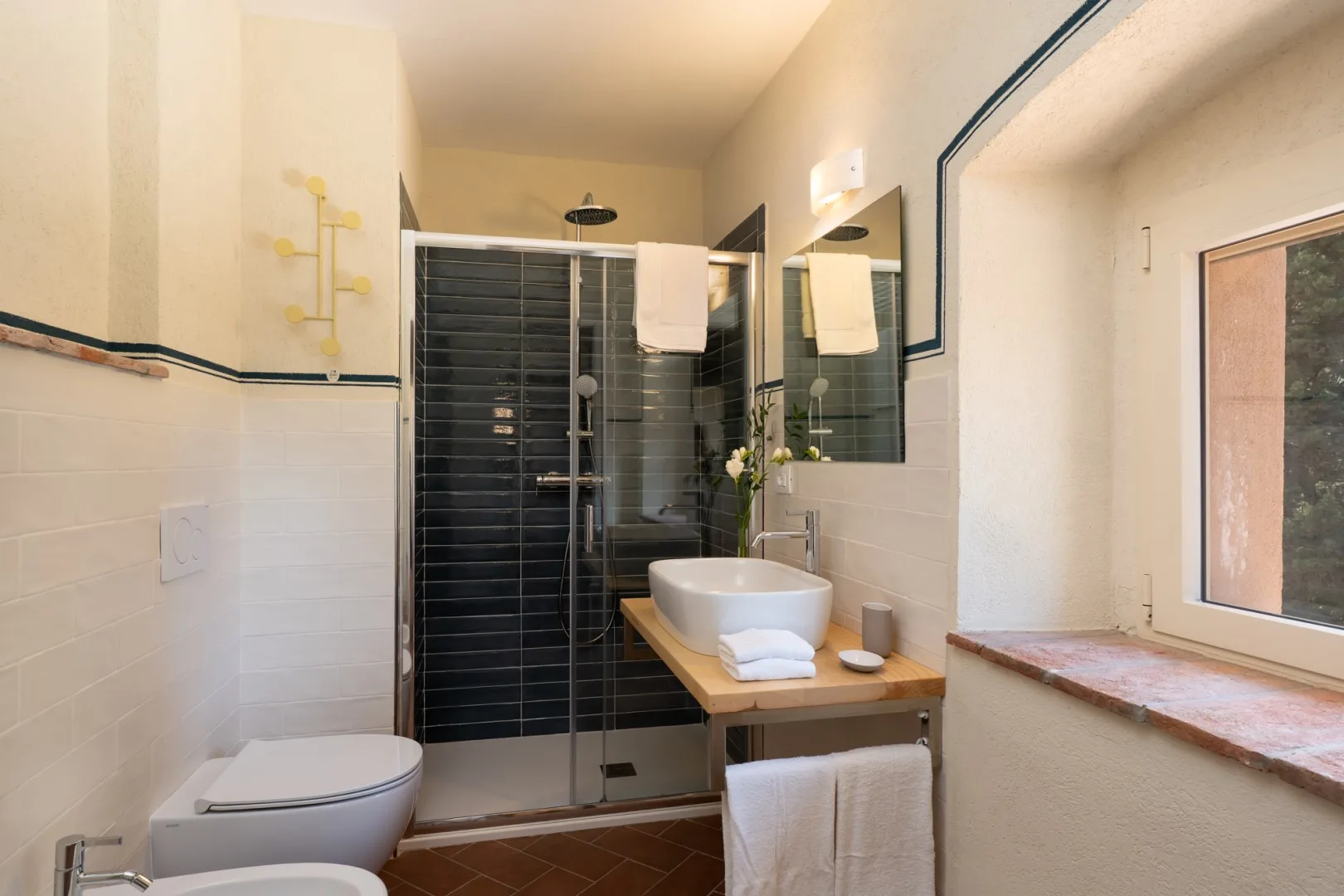 Un baño con ducha de vidrio, lavabo blanco y ventana.