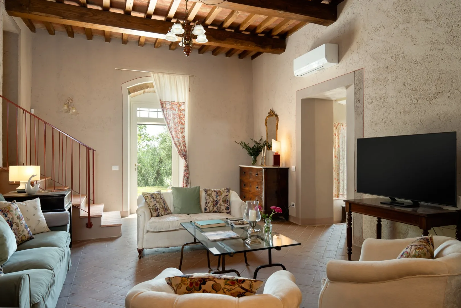 Una sala de estar con asientos alrededor de una mesa de centro de vidrio y un televisor.