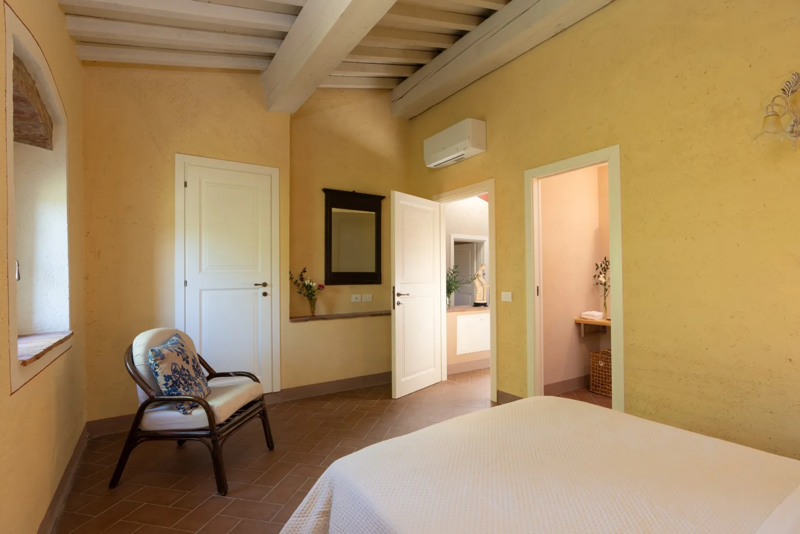 Un dormitorio con una cama, una silla y dos puertas abiertas.