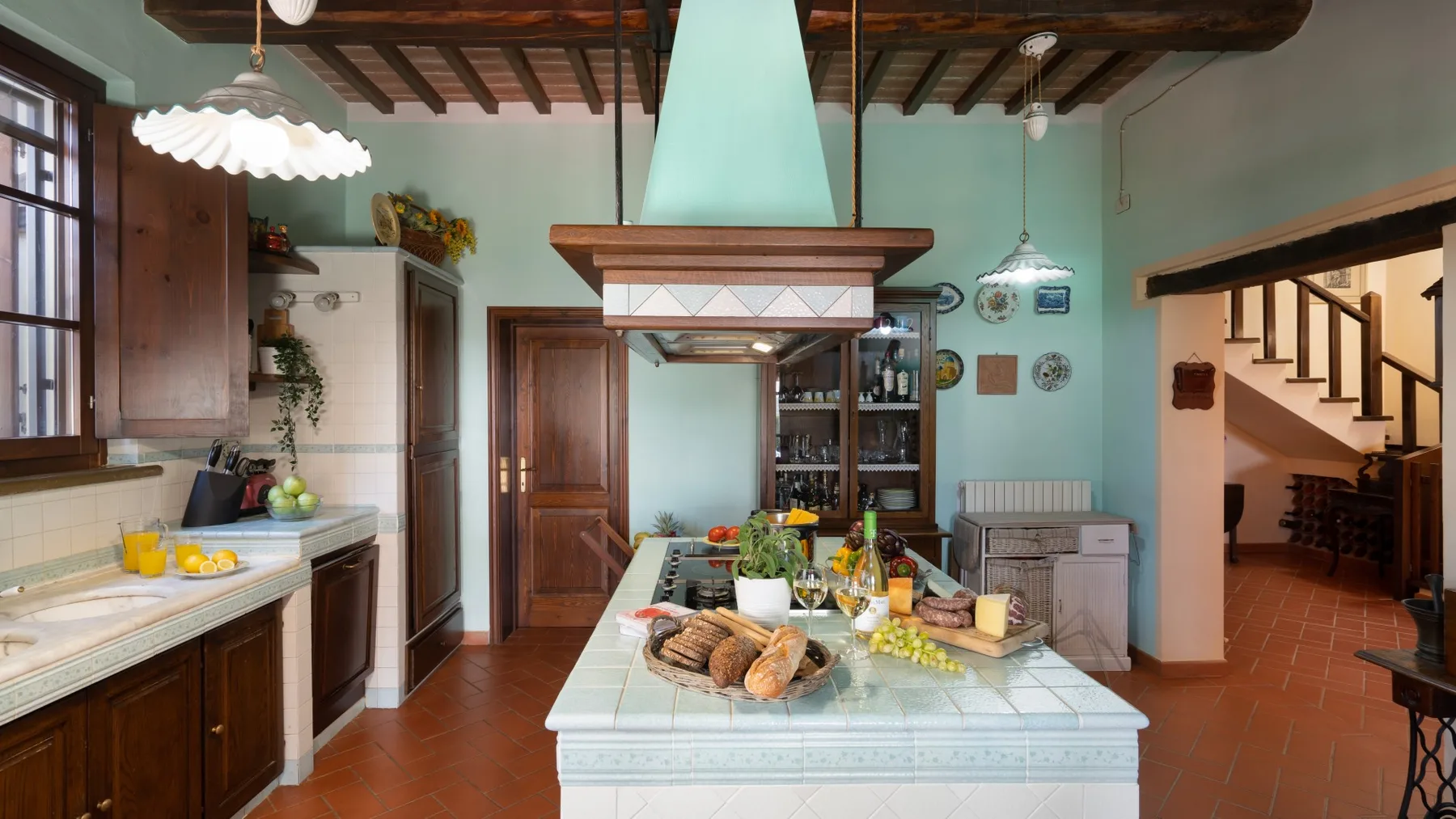 Una cocina amplia con una isla de azulejos y vigas de madera en el techo.