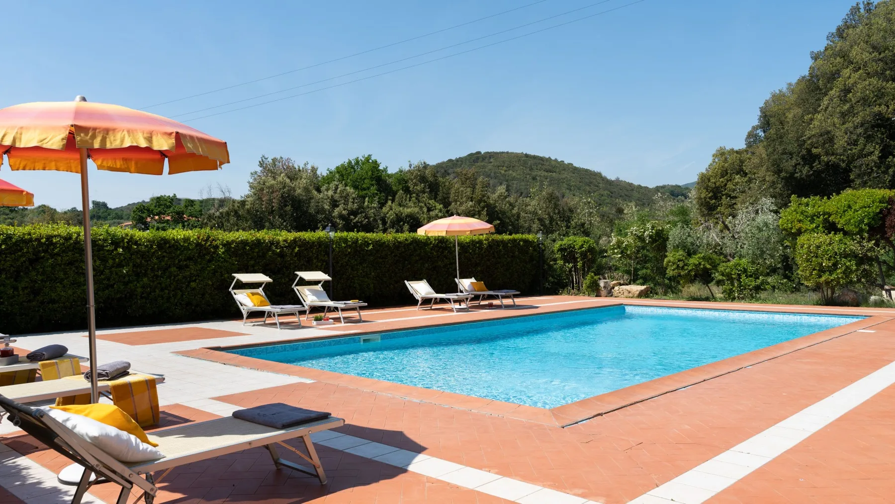 Una piscina al aire libre está rodeada por una terraza de baldosas y asientos para descansar.