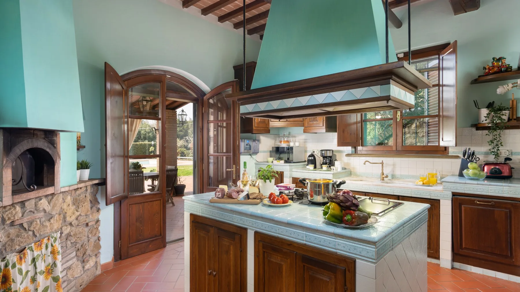 Una cocina con una isla central y una gran campana extractora turquesa.