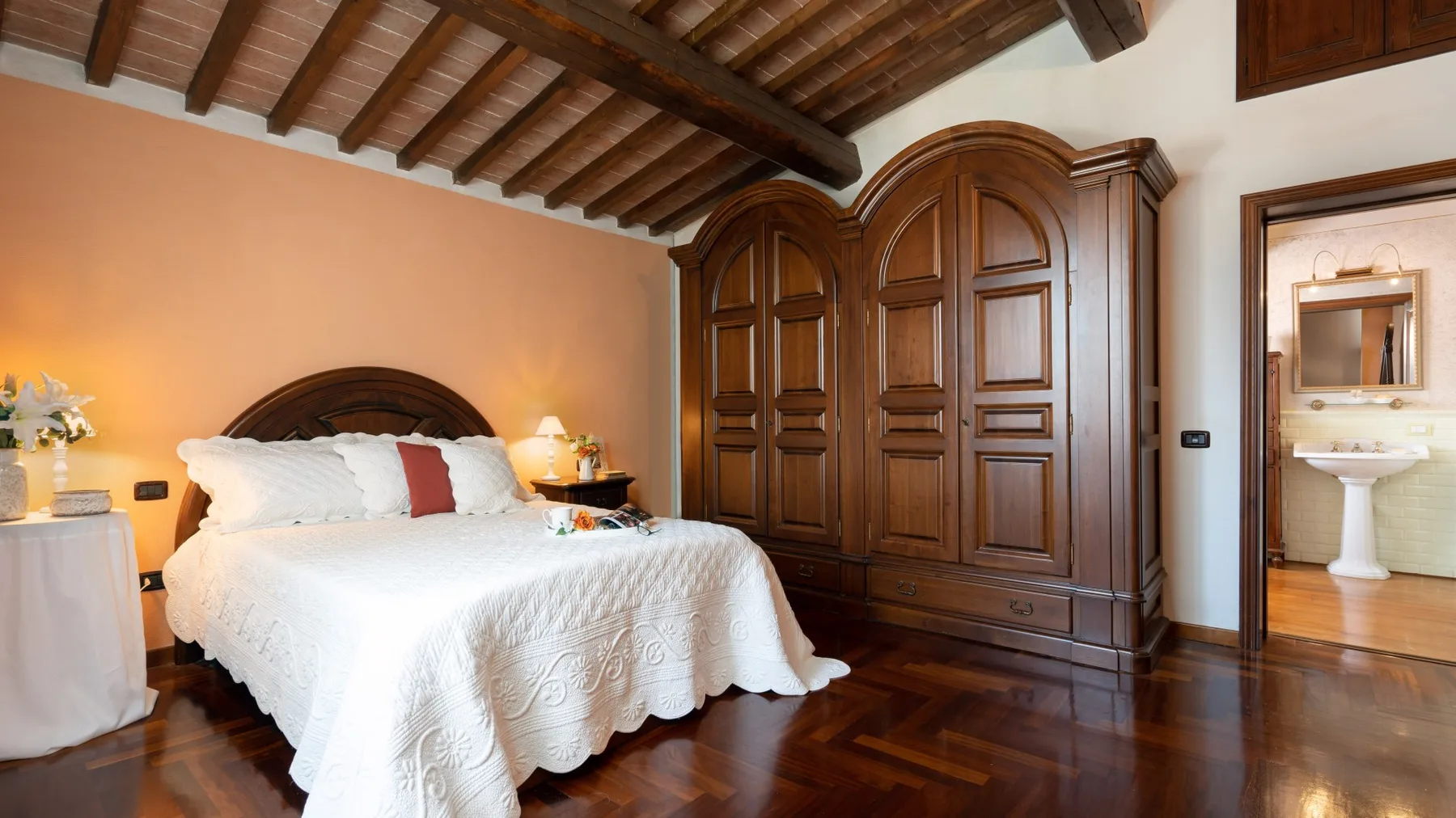 Dormitorio con cama, armario de madera y vigas de techo a la vista.