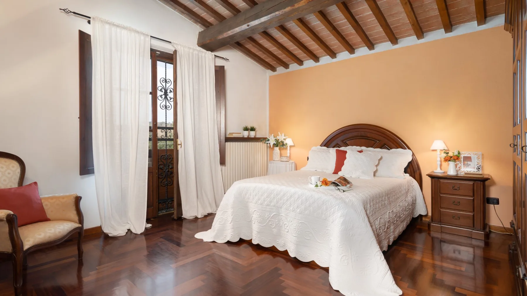 Un dormitorio con una cama, mesitas de noche y vigas de madera vistas en el techo.