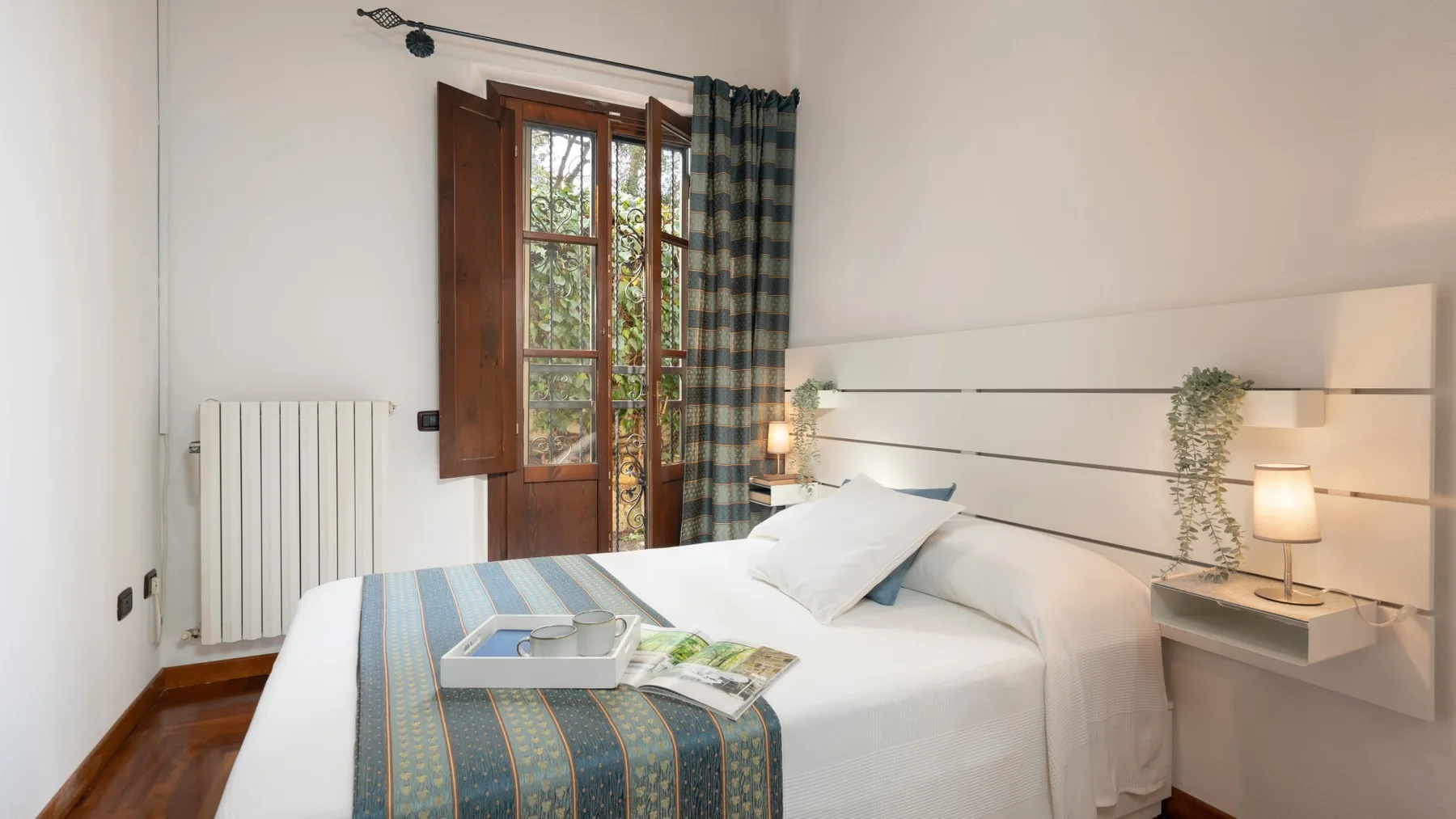 Un dormitorio con una cama, una colcha a rayas y una ventana con marco de madera.