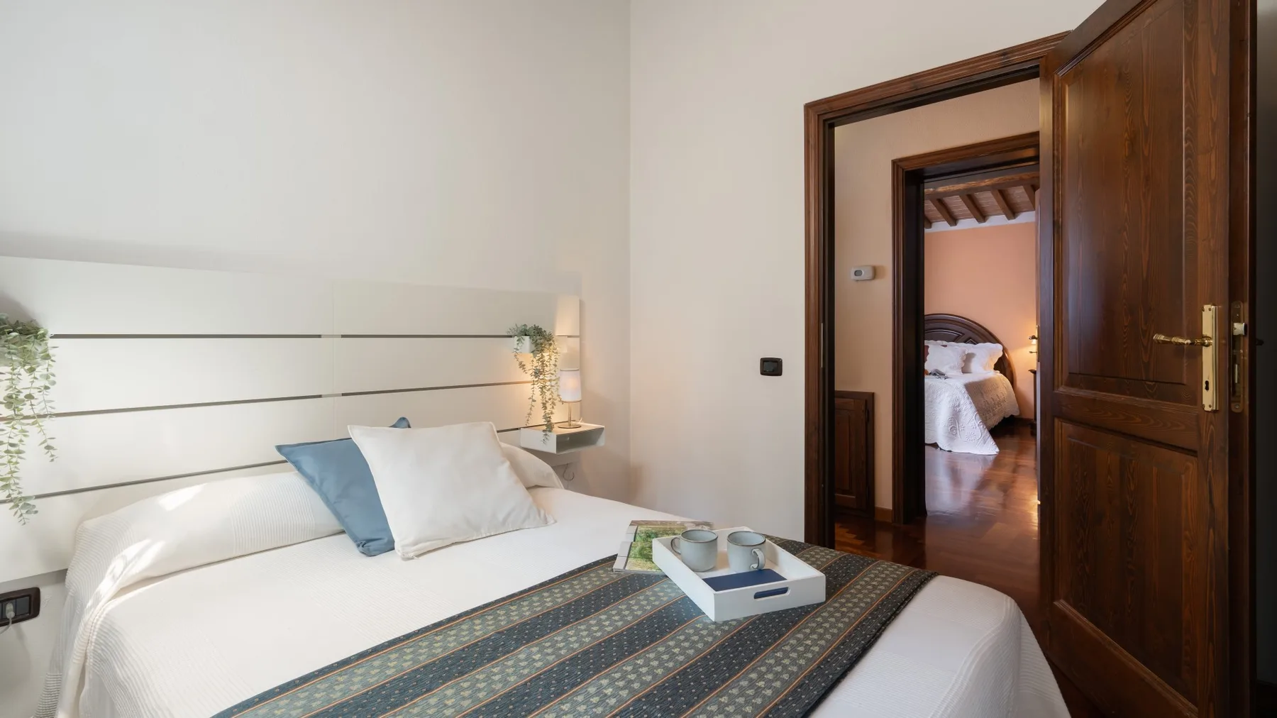 Un dormitorio con una cama bien arreglada y una puerta abierta a otra habitación.