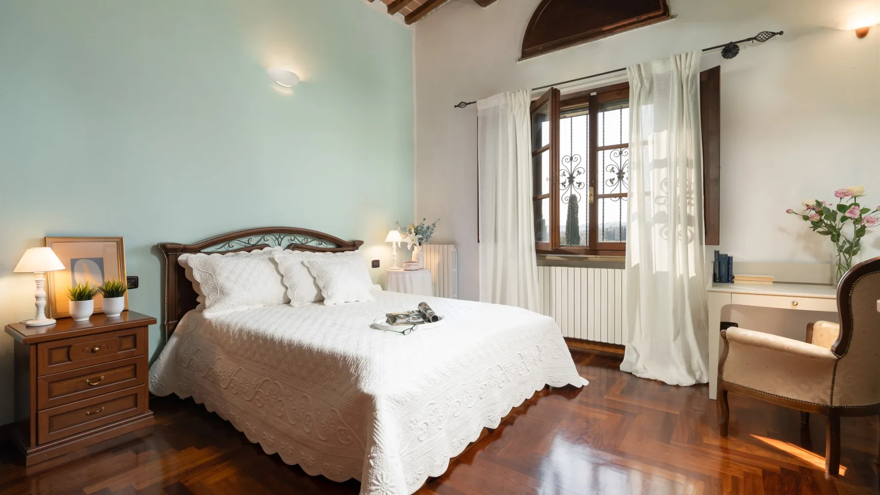 Un dormitorio con una cama, una mesita de noche y una ventana con cortinas.
