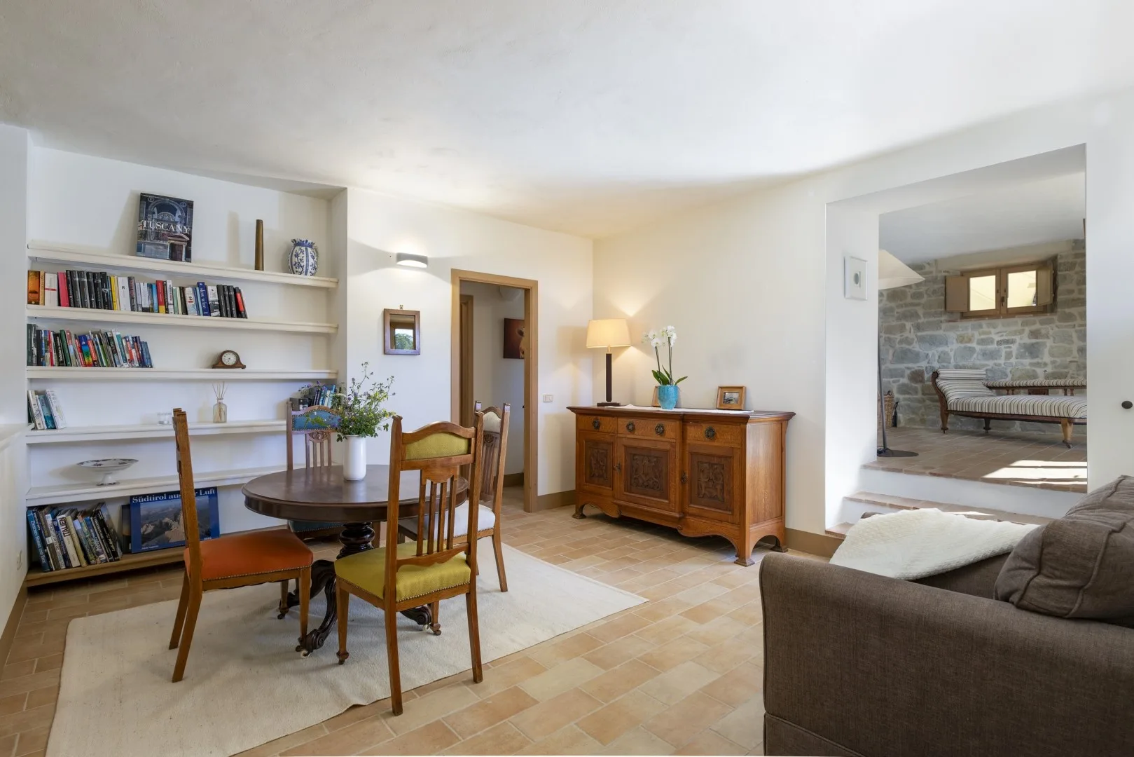 Una luminosa sala de estar y comedor tiene una mesa de madera, estanterías empotradas y un aparador.