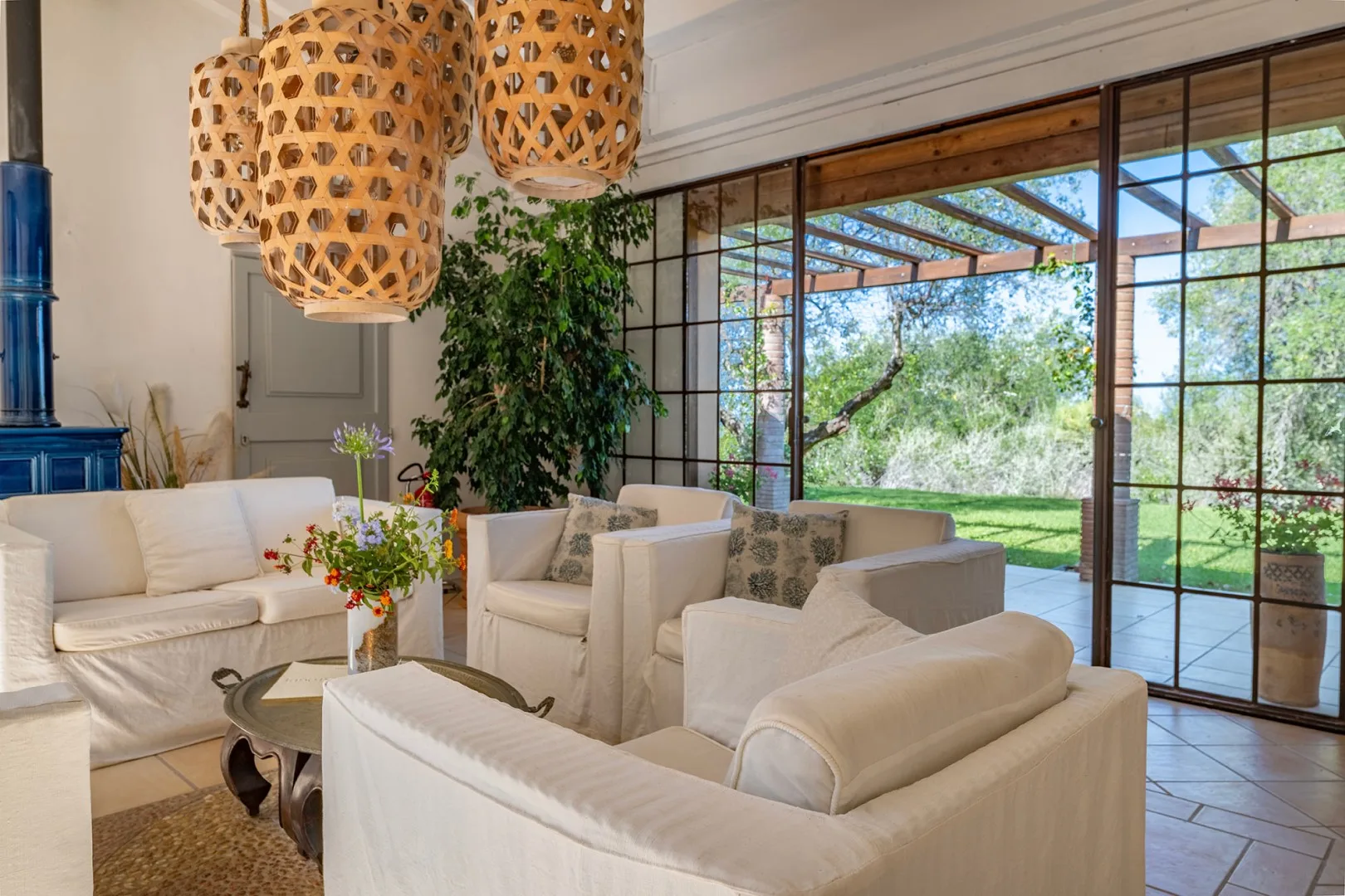 Una sala luminosa con asientos claros junto a grandes puertas de vidrio que dan a un jardín.
