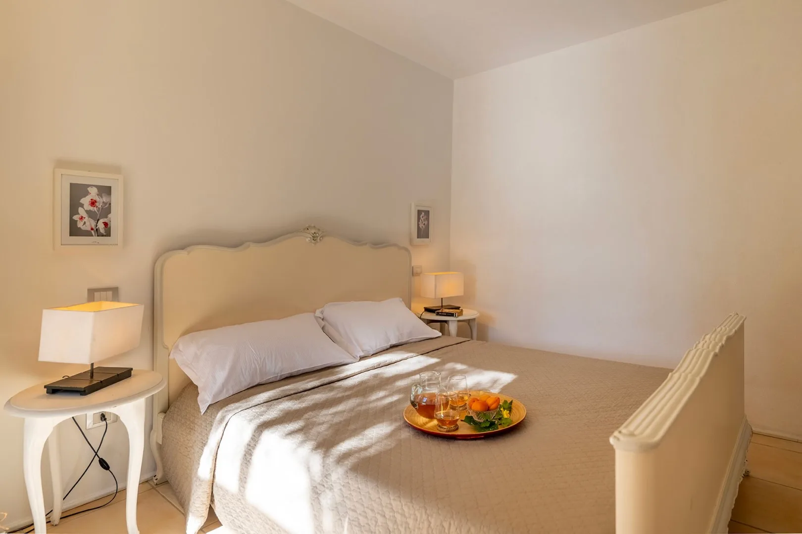 Un dormitorio con una cama, mesitas de noche y cuadros en la pared.