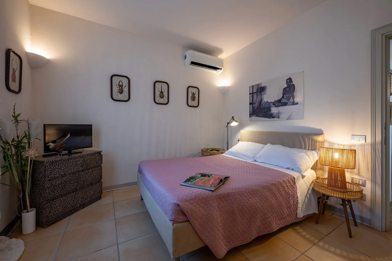 Un dormitorio con una cama, mesitas de noche y un televisor sobre una cómoda.