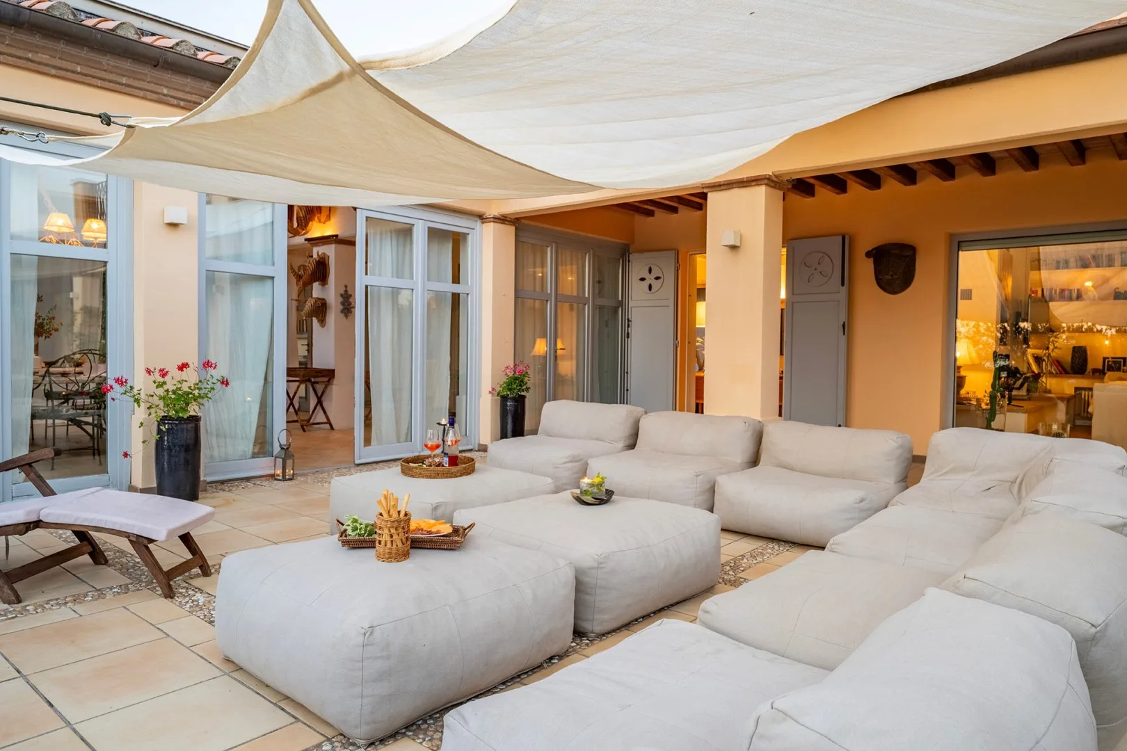Una sala al aire libre con asientos acolchados bajo una cubierta de tela.