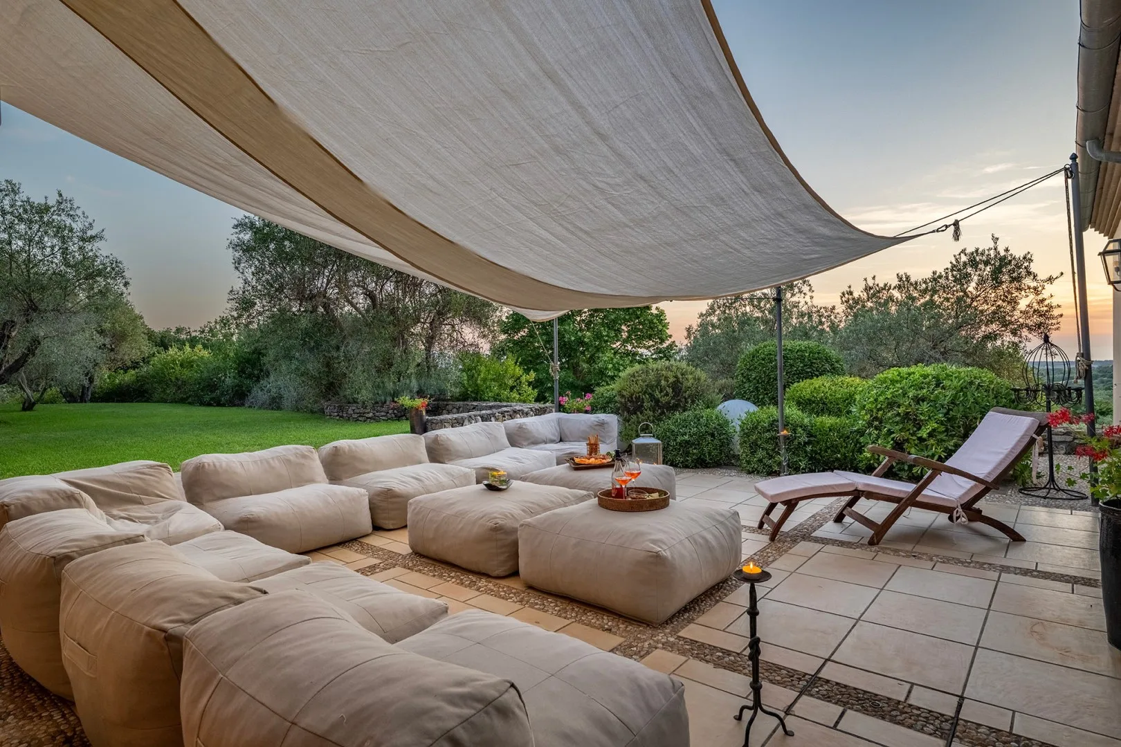 Un salón al aire libre con asientos acolchados bajo una cubierta de tela.