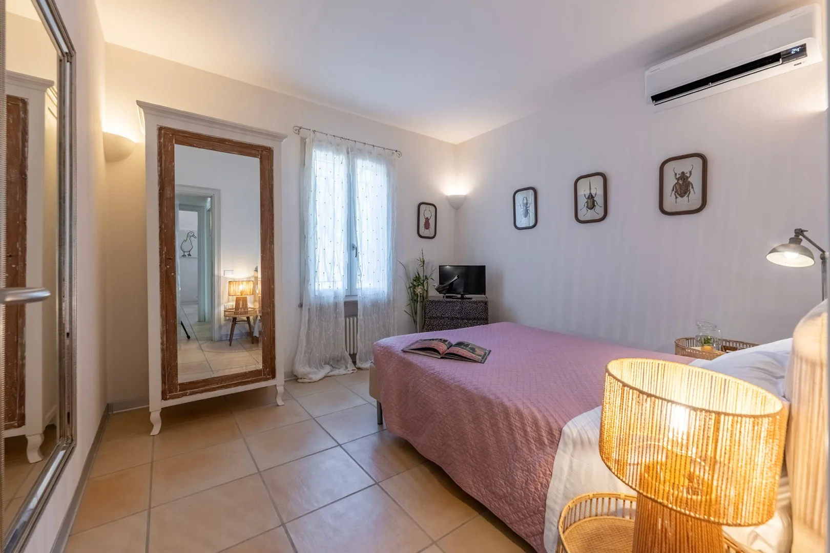 Un dormitorio con una cama, una ventana con cortinas y cuadros en la pared.