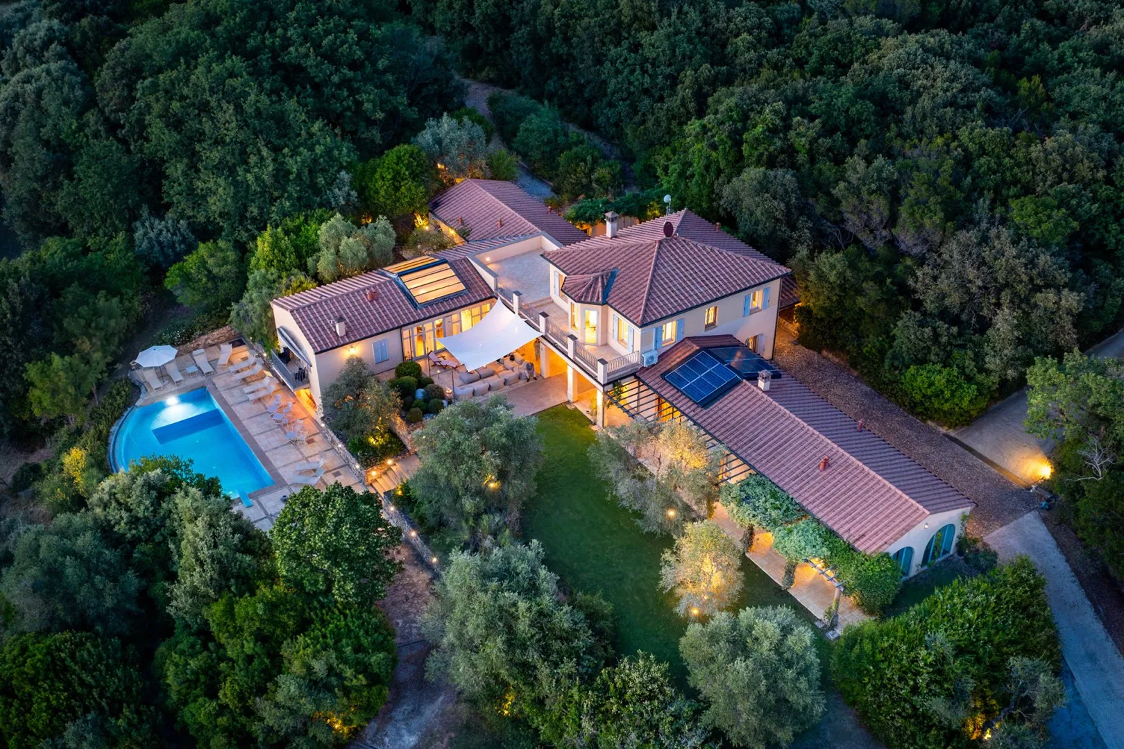 Una vista aérea muestra una casa grande, una piscina y árboles alrededor.