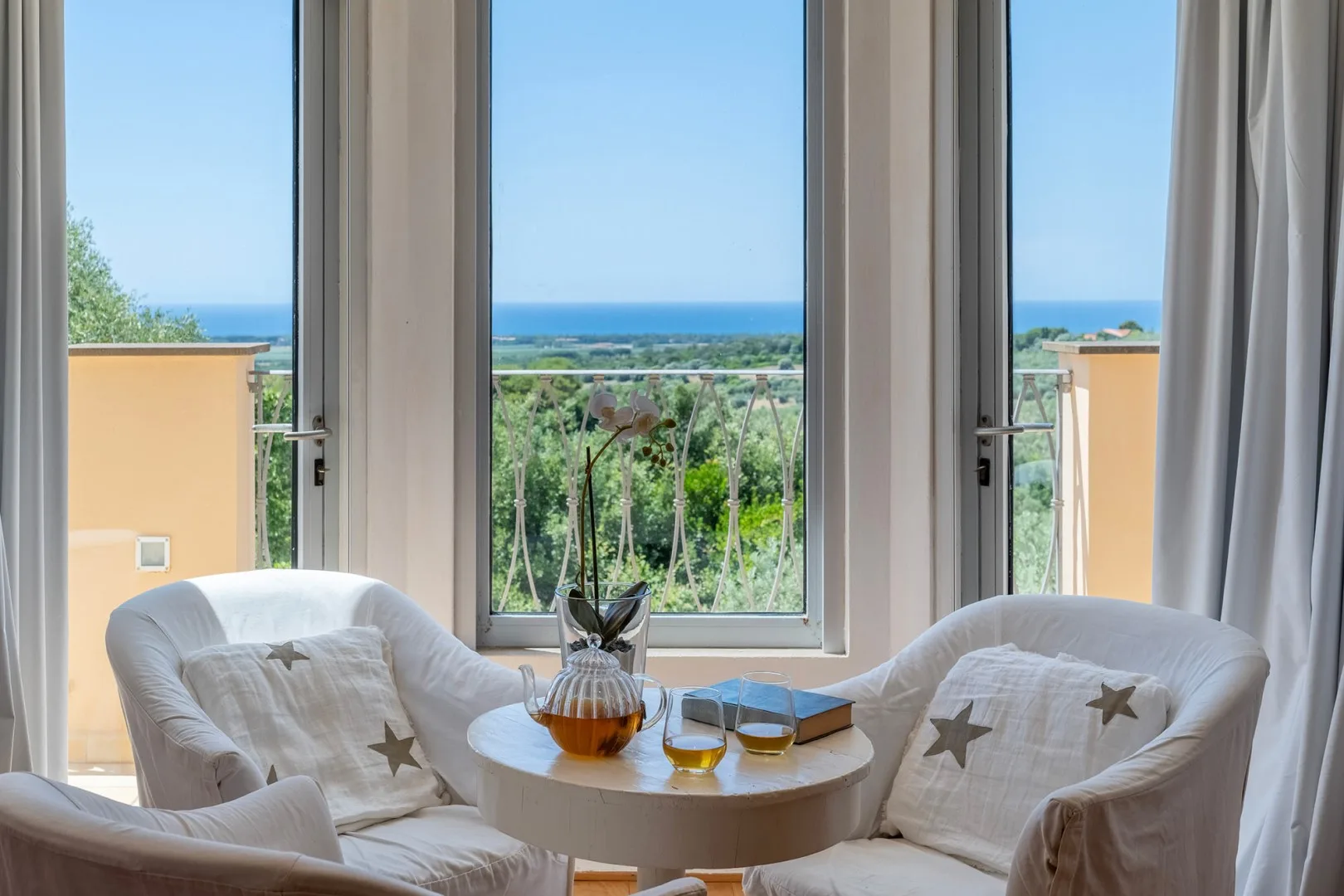 Una luminosa zona de estar con asientos acolchados y vistas al mar a través de ventanas altas.